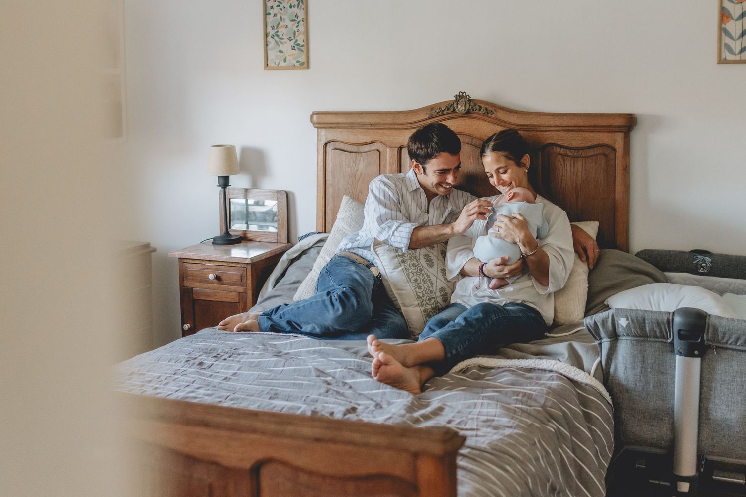 Mamá y papá en la cama con bebé recién nacido en brazos durante una sesión de fotos de recién nacido en tandil