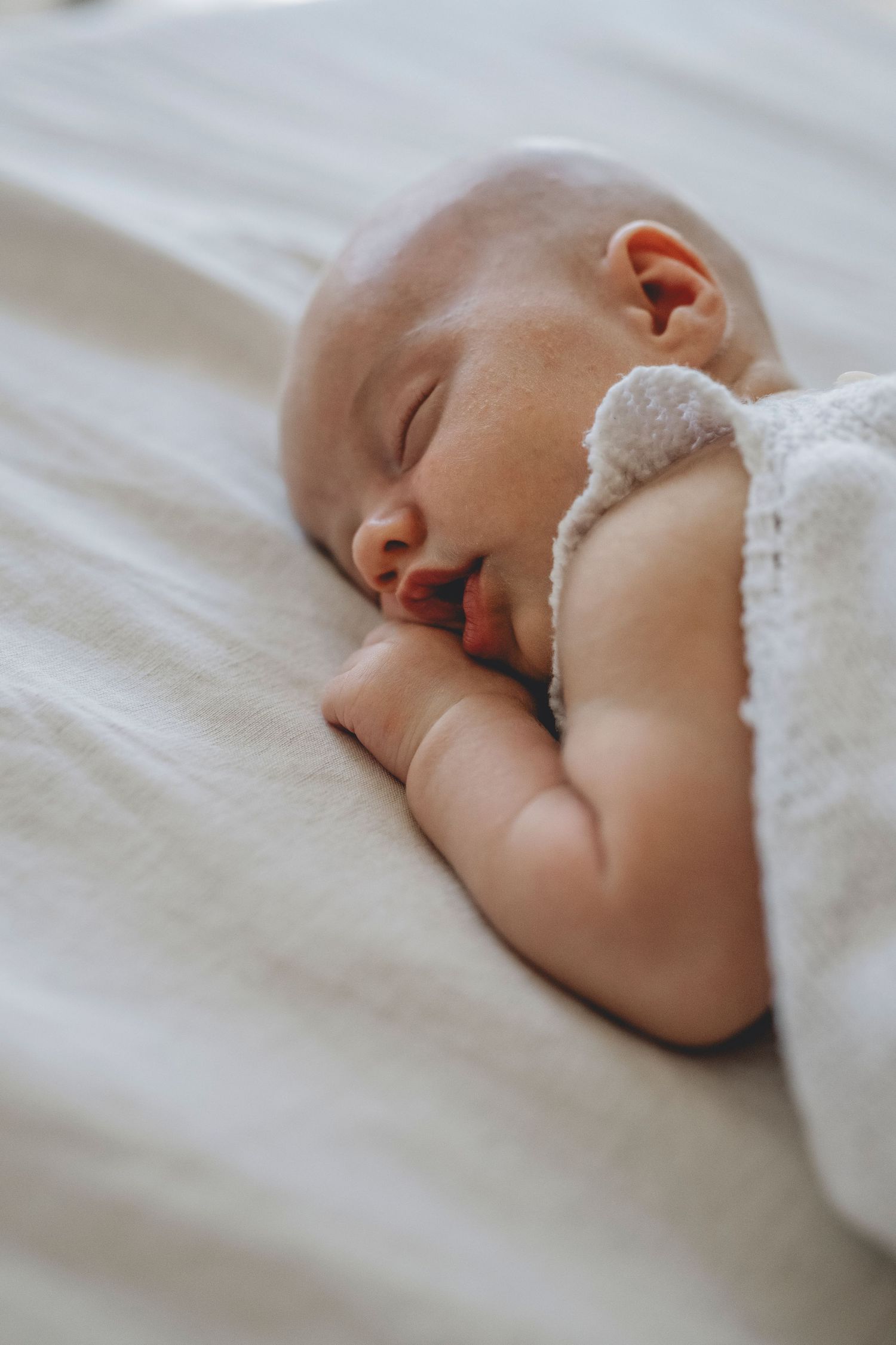 Bebé recién nacido durmiendo en la cama de sus padres durante unas sesión de fotos de recién nacido