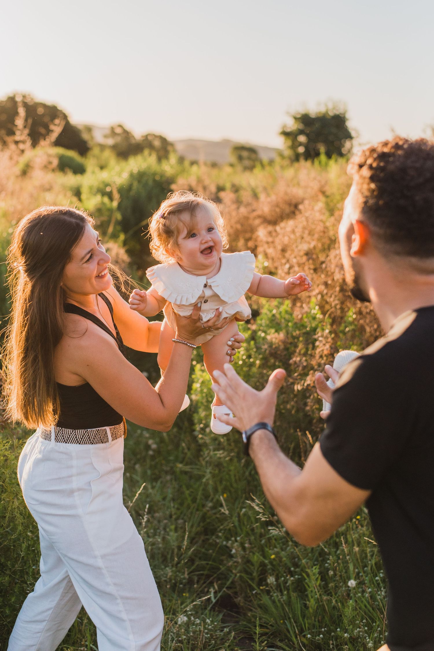 Mamá y Papá jugando con bebé de un años durante una sesión de fotos familiar en tandil