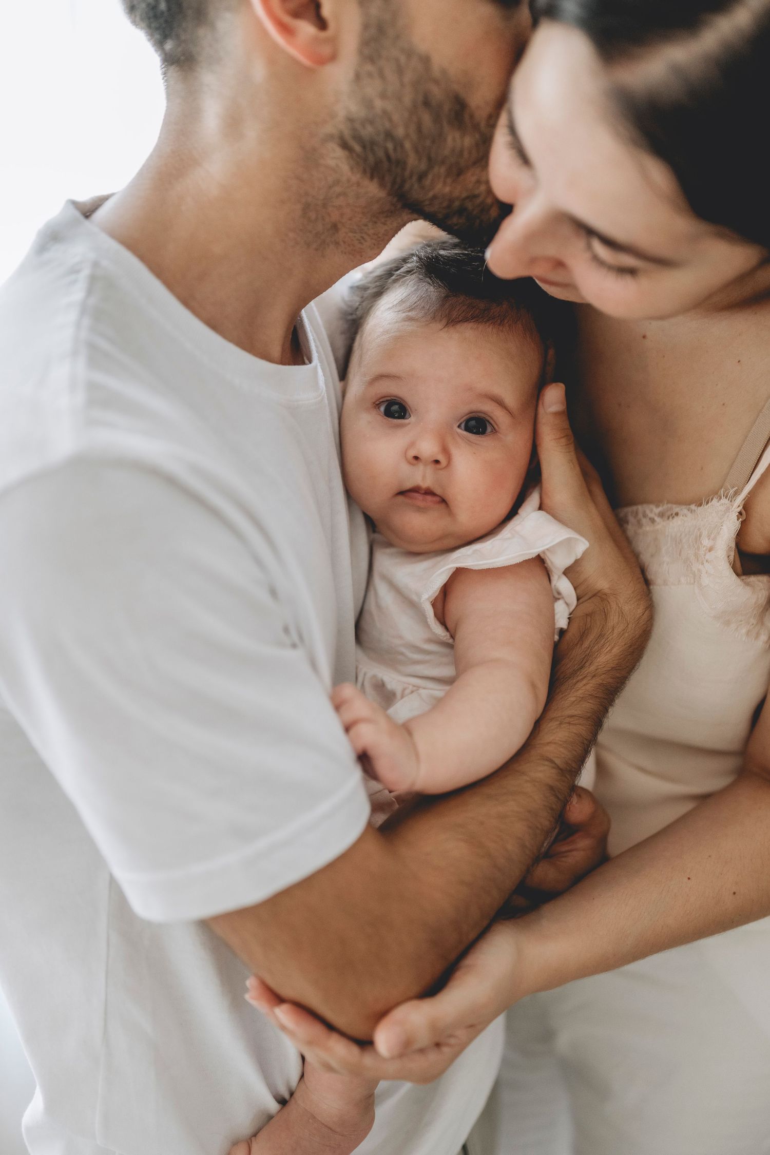 beba recién nacida entre los brazos de sus padres