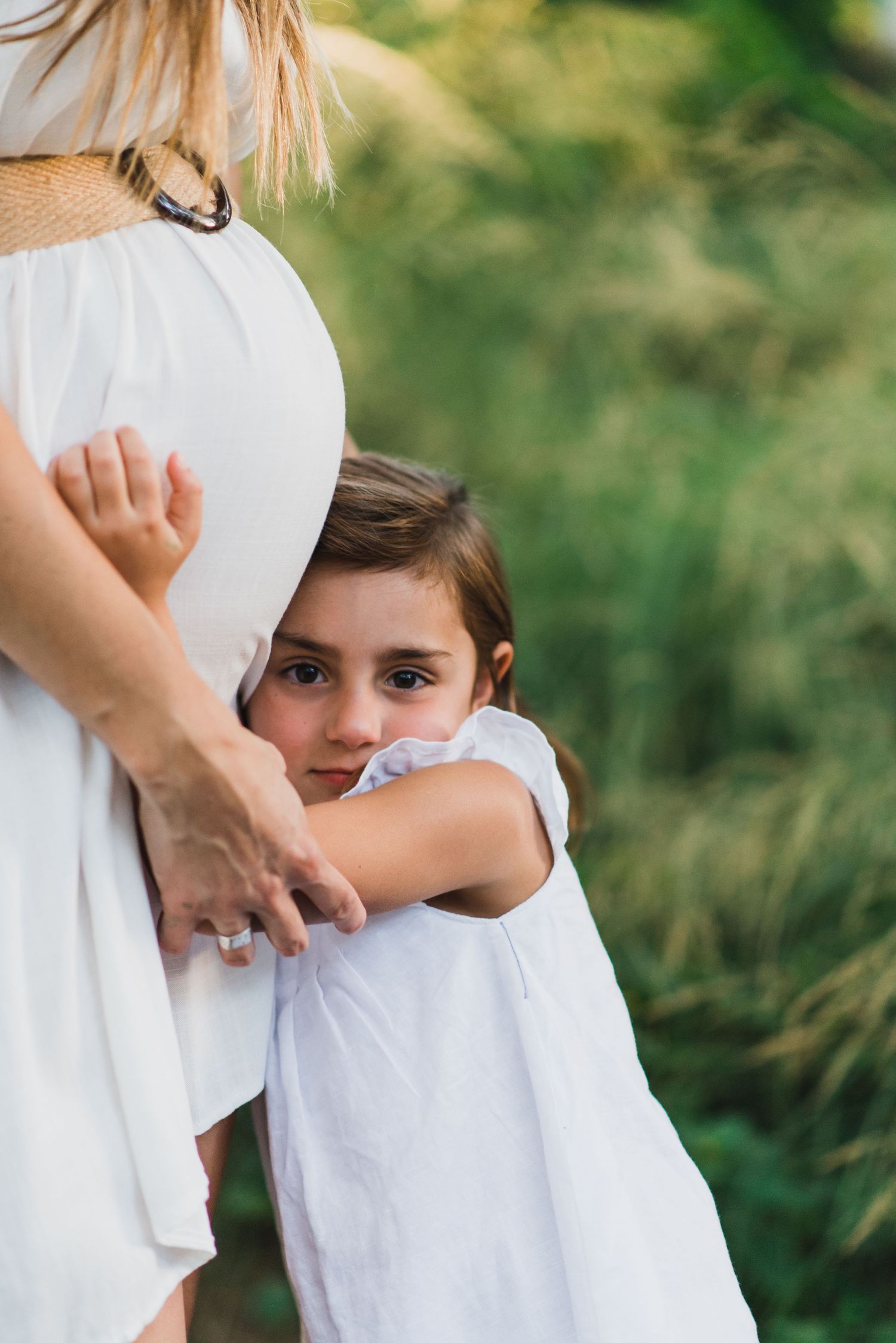Niña abrazando la panza de sus mamá embarazada