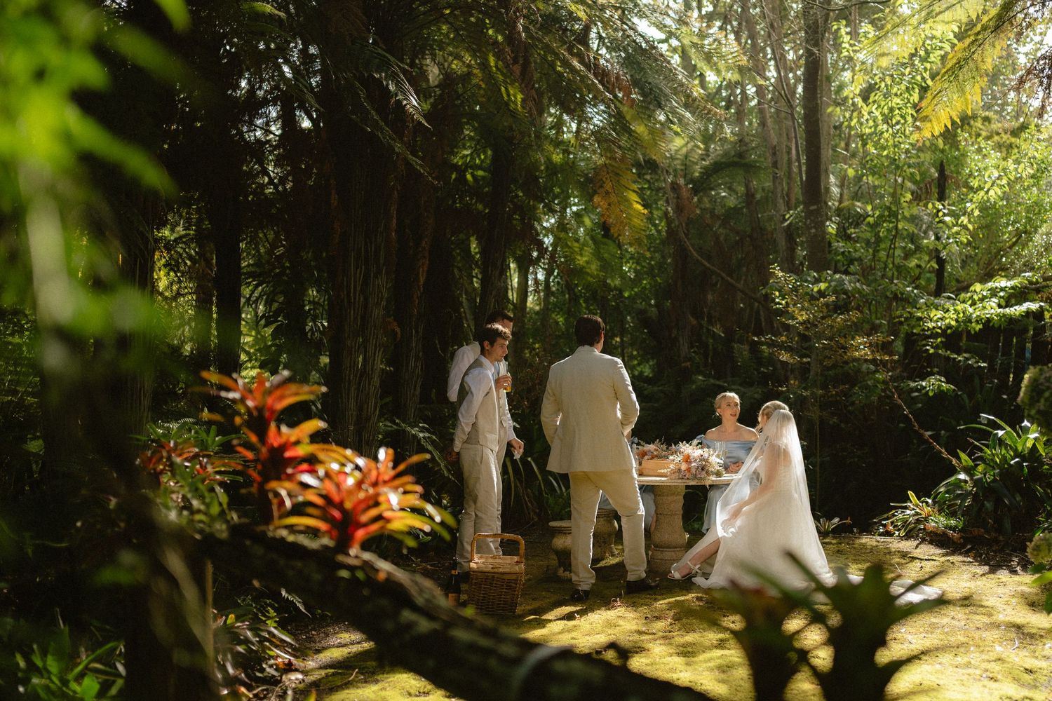 Couple exchanging vows in a lush tropical garden wedding ceremony with officiant at an outdoor altar.