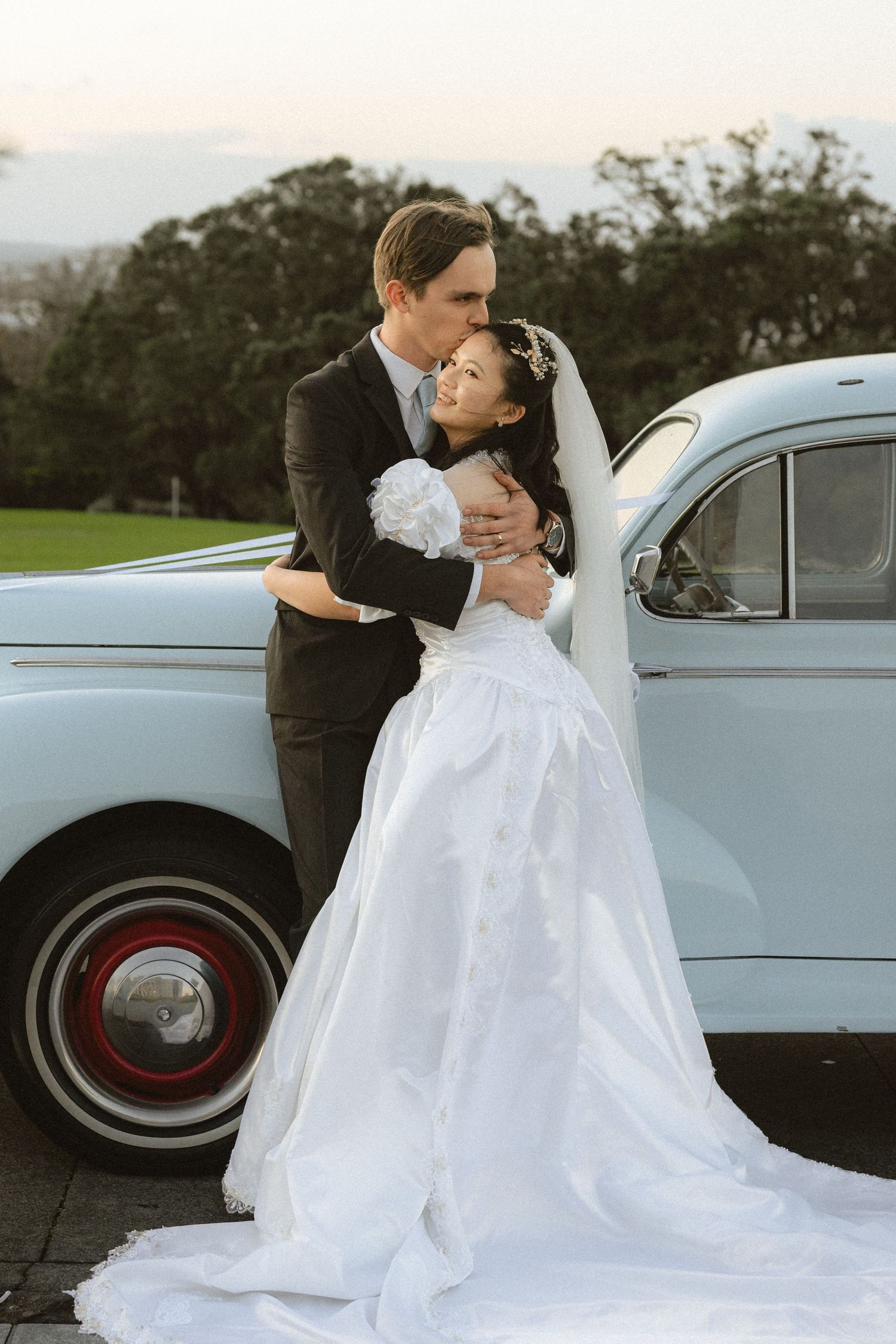 A classic wedding photoshoot featuring a couple posing with a vintage light blue car.