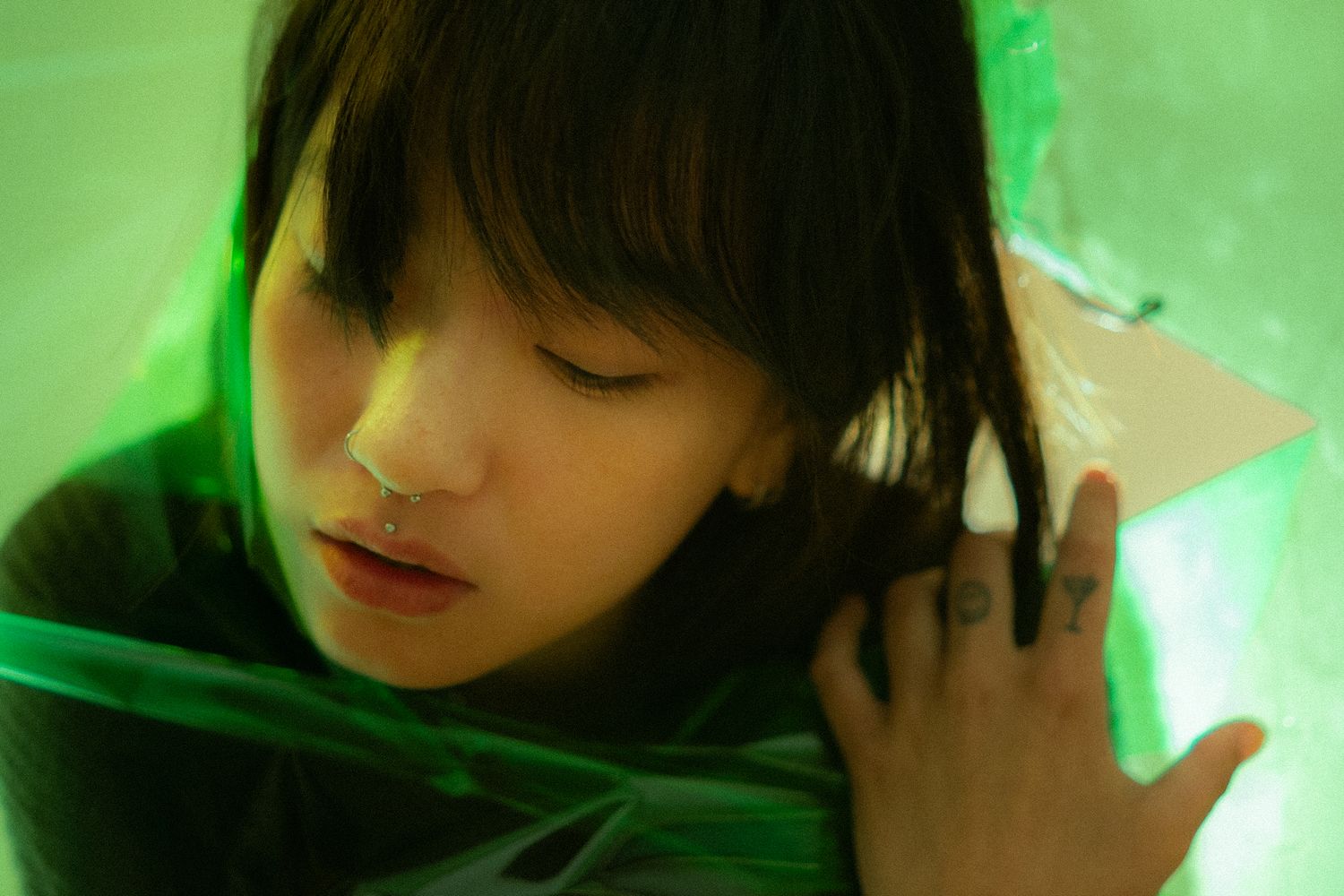 A girl poking her head through a transparent green paper.