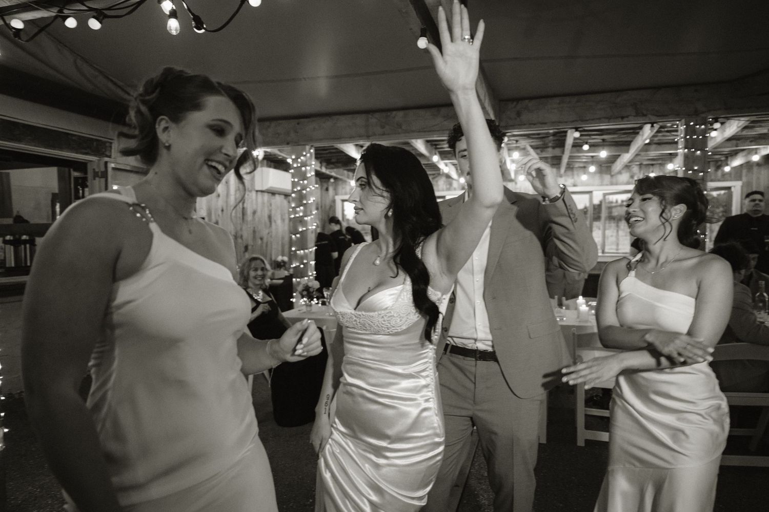 Black and white photo of bridesmaids dancing joyfully at a wedding reception venue.
