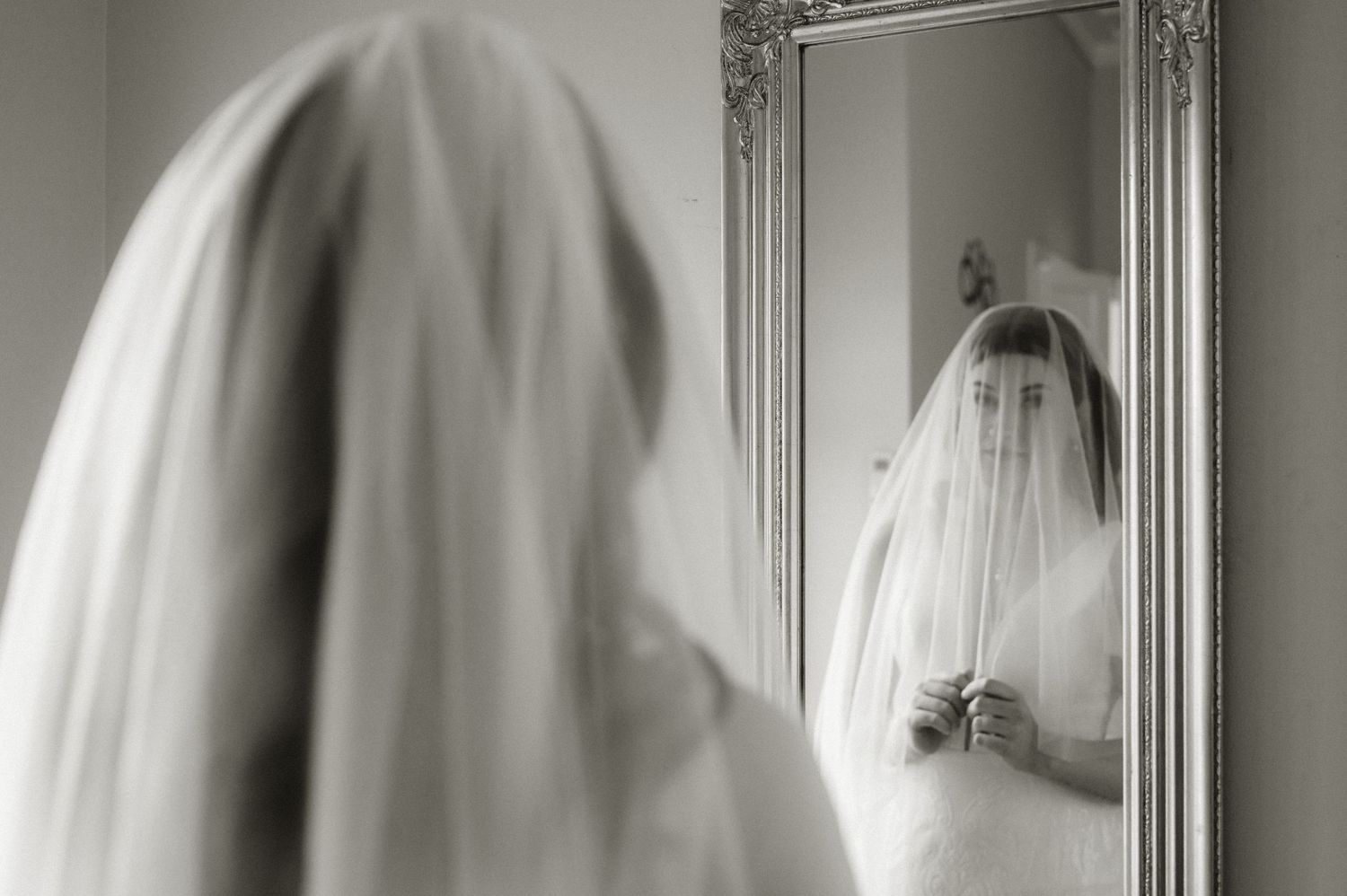 Artistic black and white sequence of a wedding veil flowing in front of an ornate mirror.