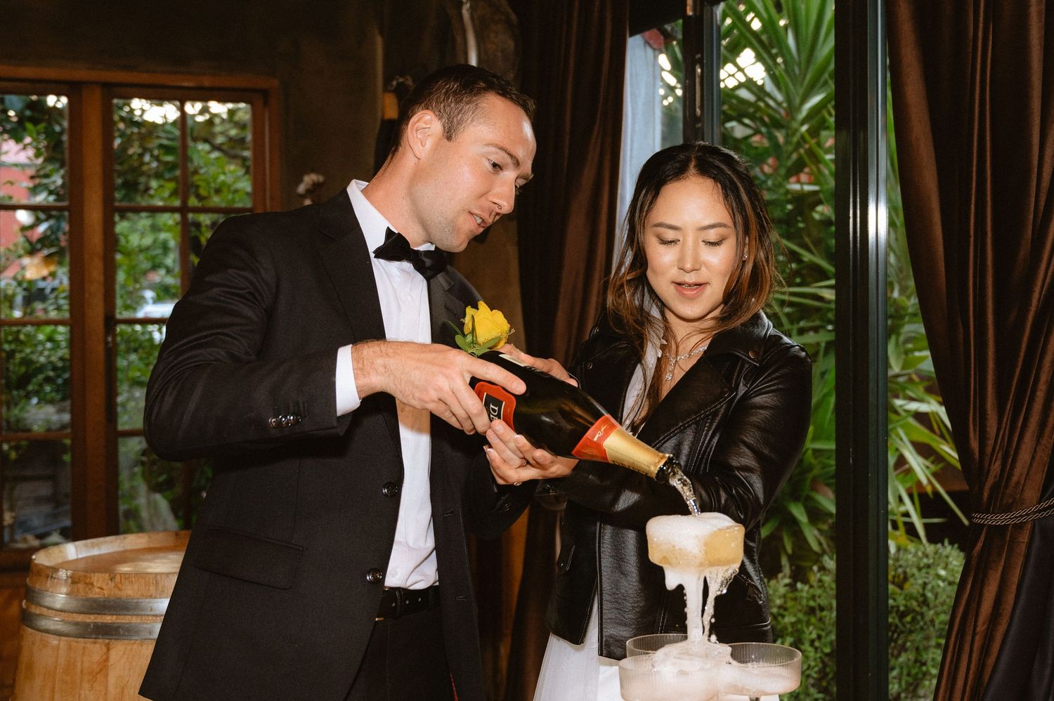 Bride and groom at their wedding reception pouring champagne into a champagne tower