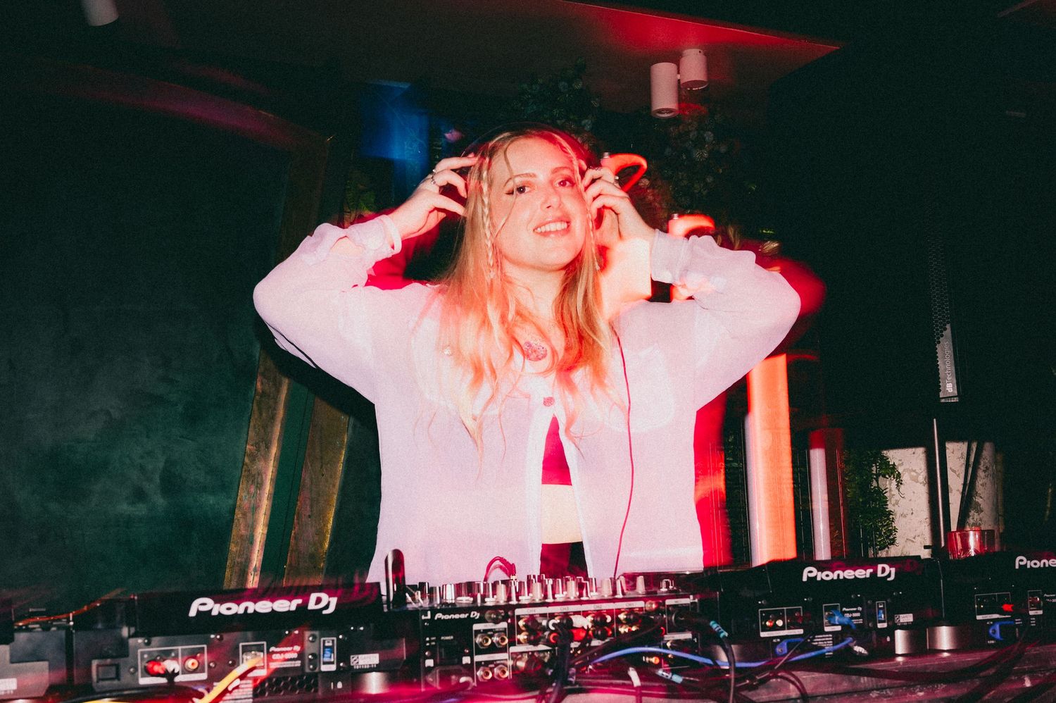 Cool DJ girl adjusting her headphones and smiling at the crowd.