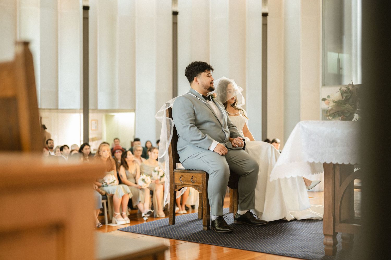 Filipino bride and groom sitting at the altar during their traditional veil and cord ceremony.