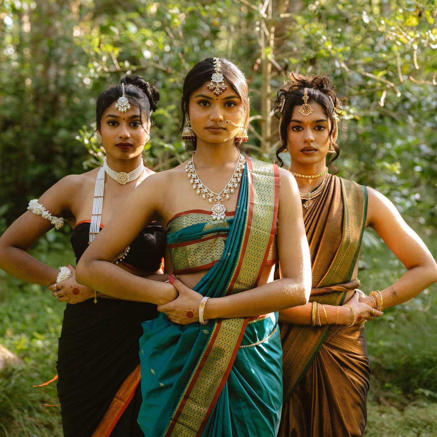 Dancers in colorful saris posing together in a garden setting.