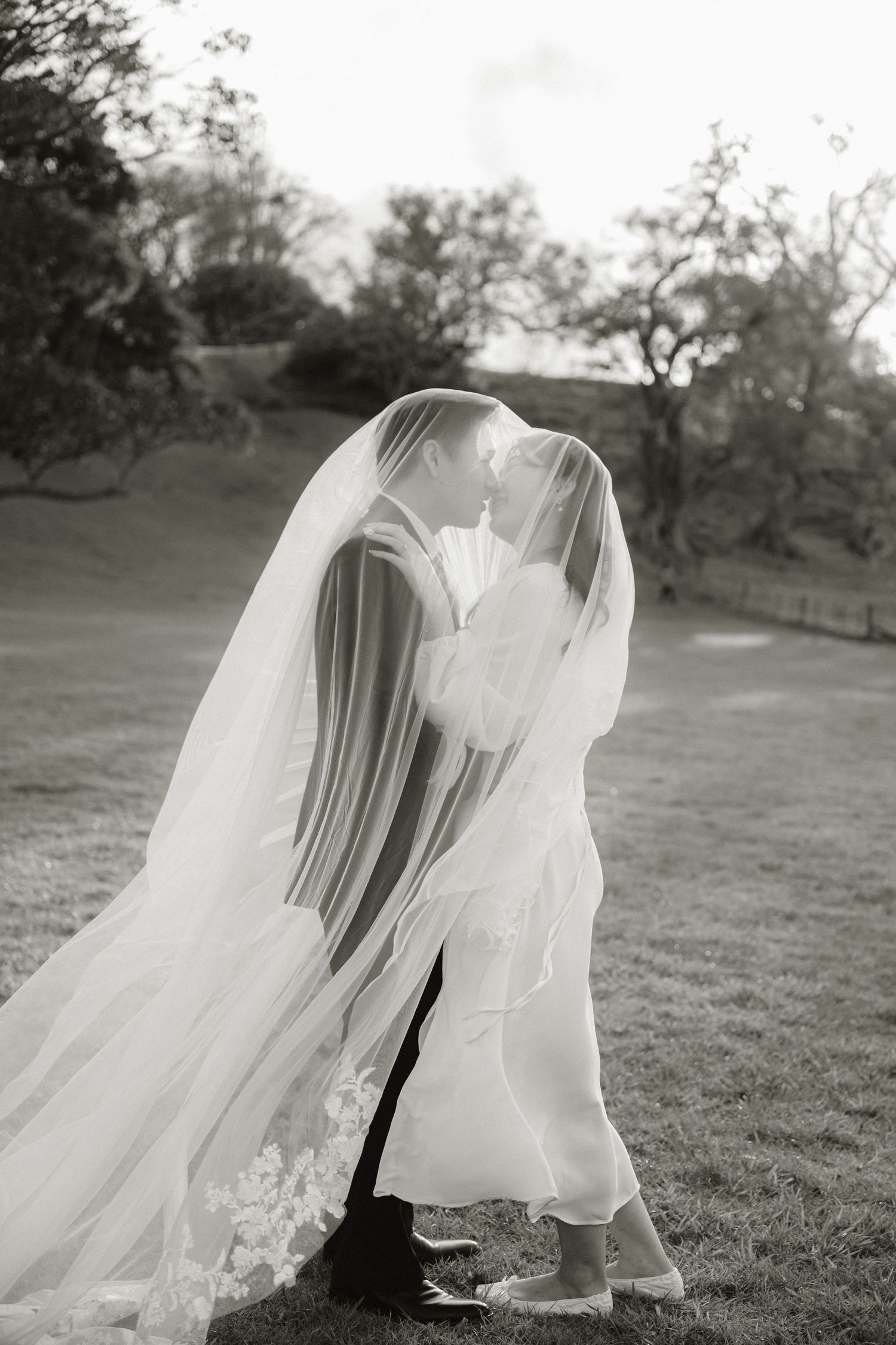 A romantic sequence of black and white photos showing a flowing wedding dress veil blowing in the wind across a grassy field.