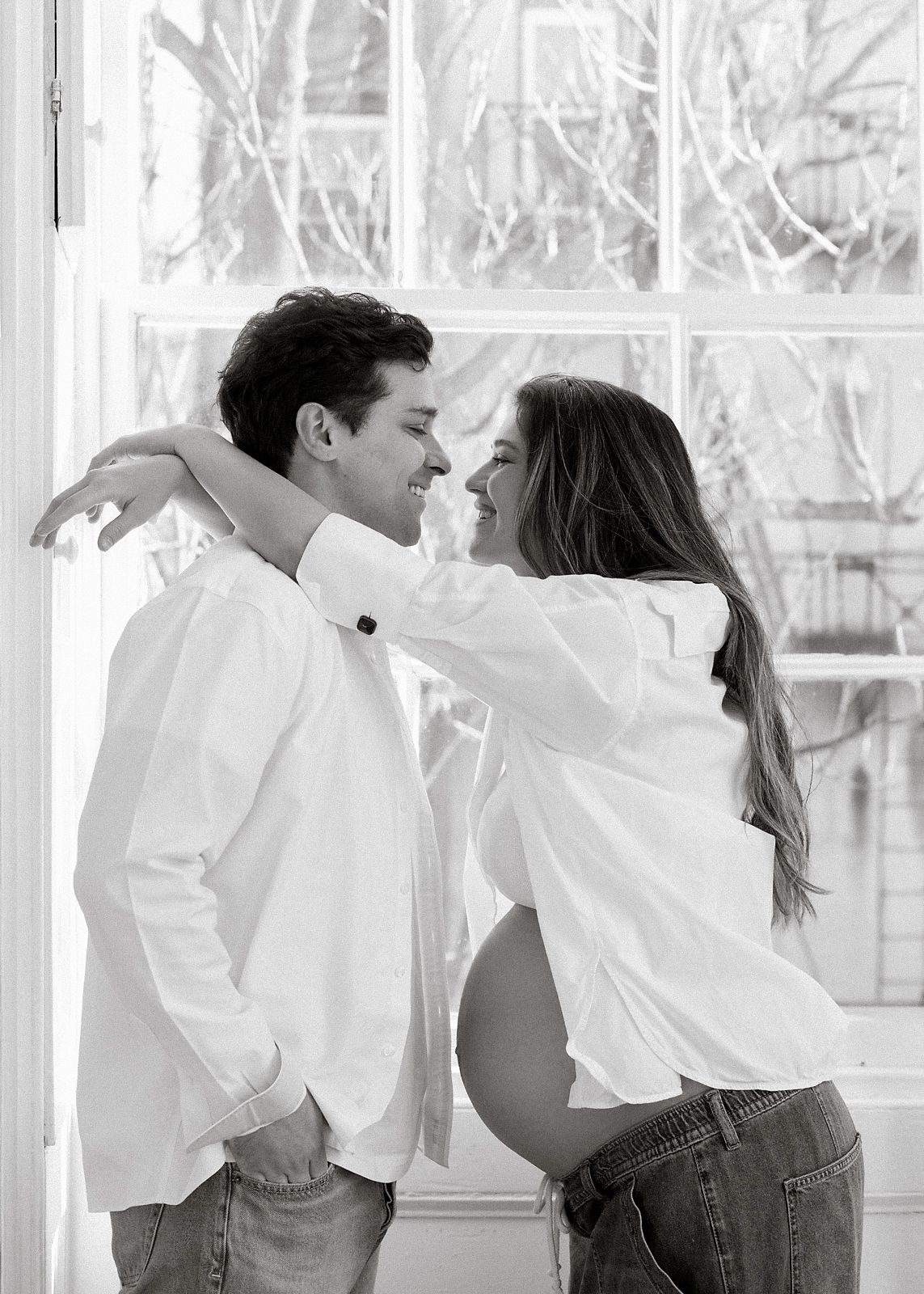 Black and white photo series showing a couple in white shirts and jeans dancing together in a bright interior space.