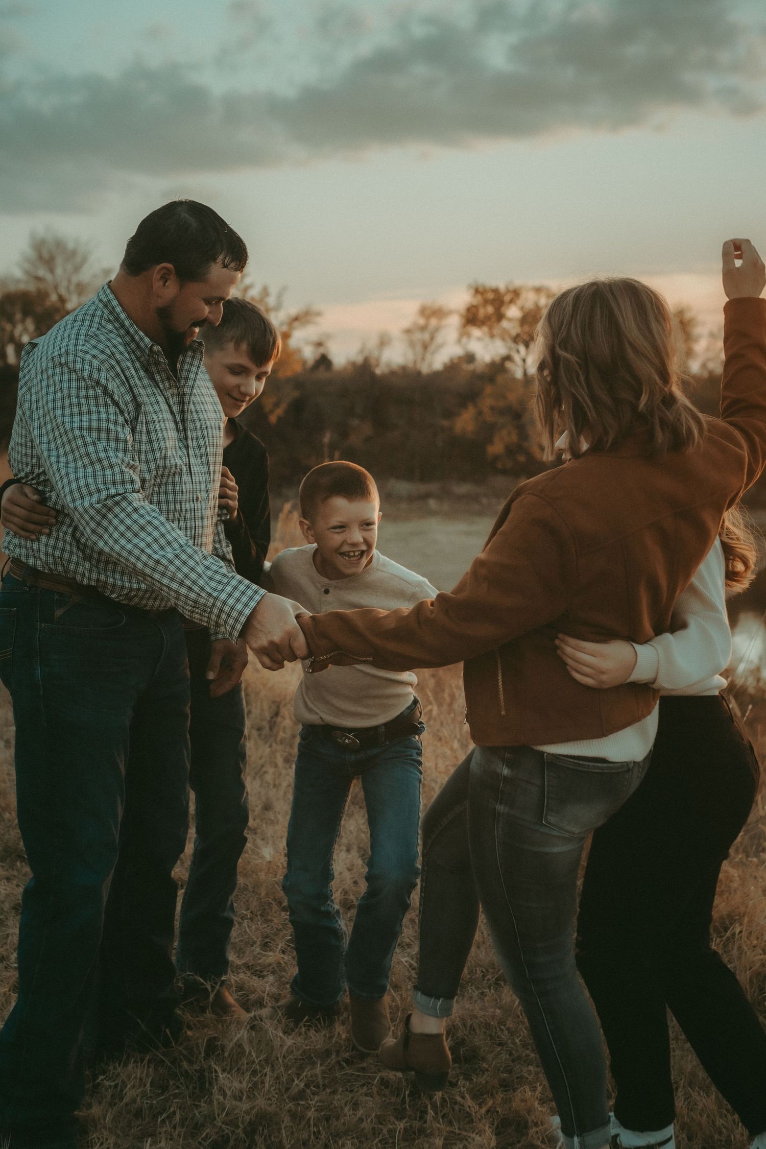 Family laughing in tall grass – candid family moments photographed in Kansas