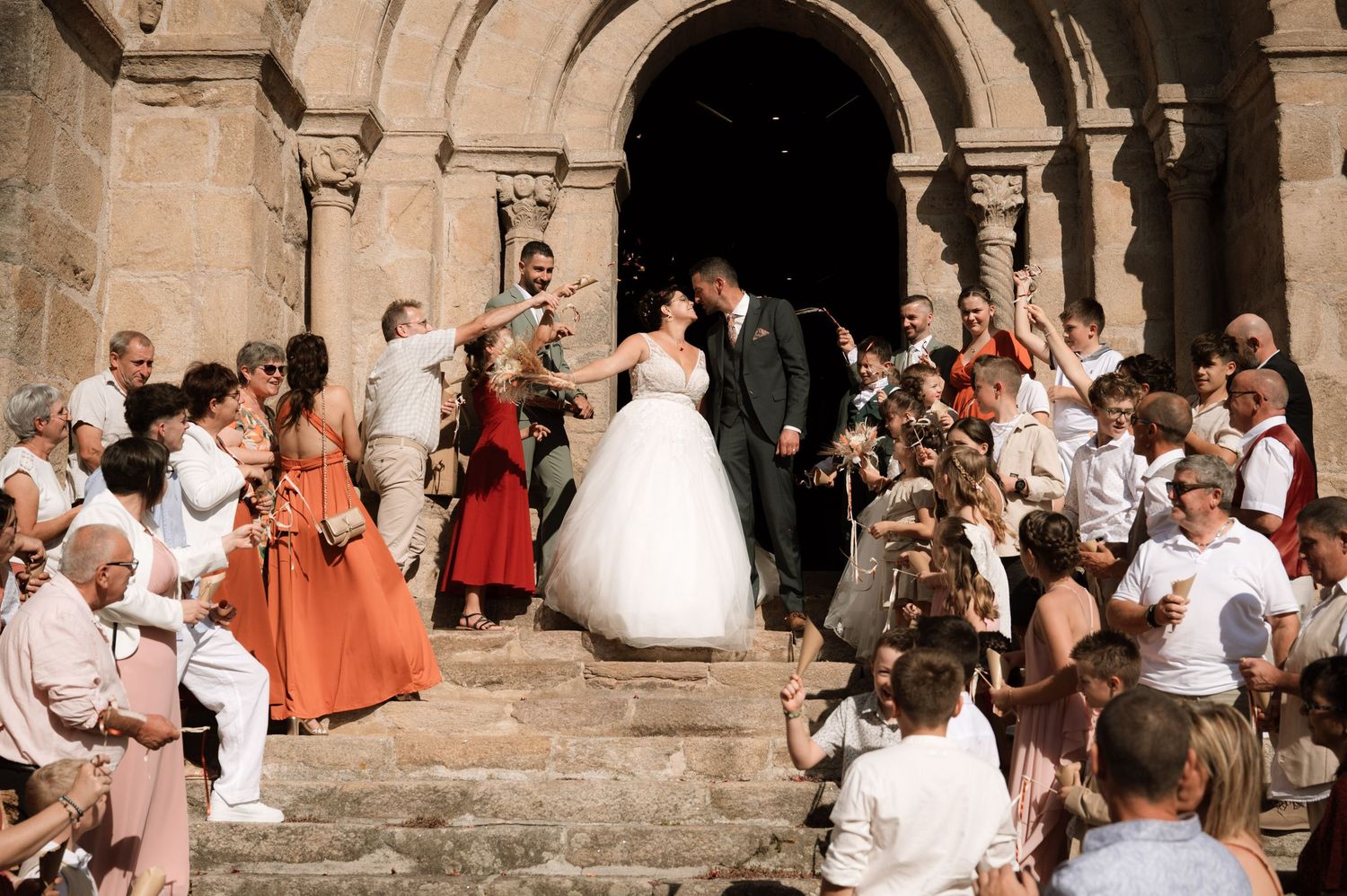 Wedding guests gather outside a historic stone church entrance during a summer celebration.