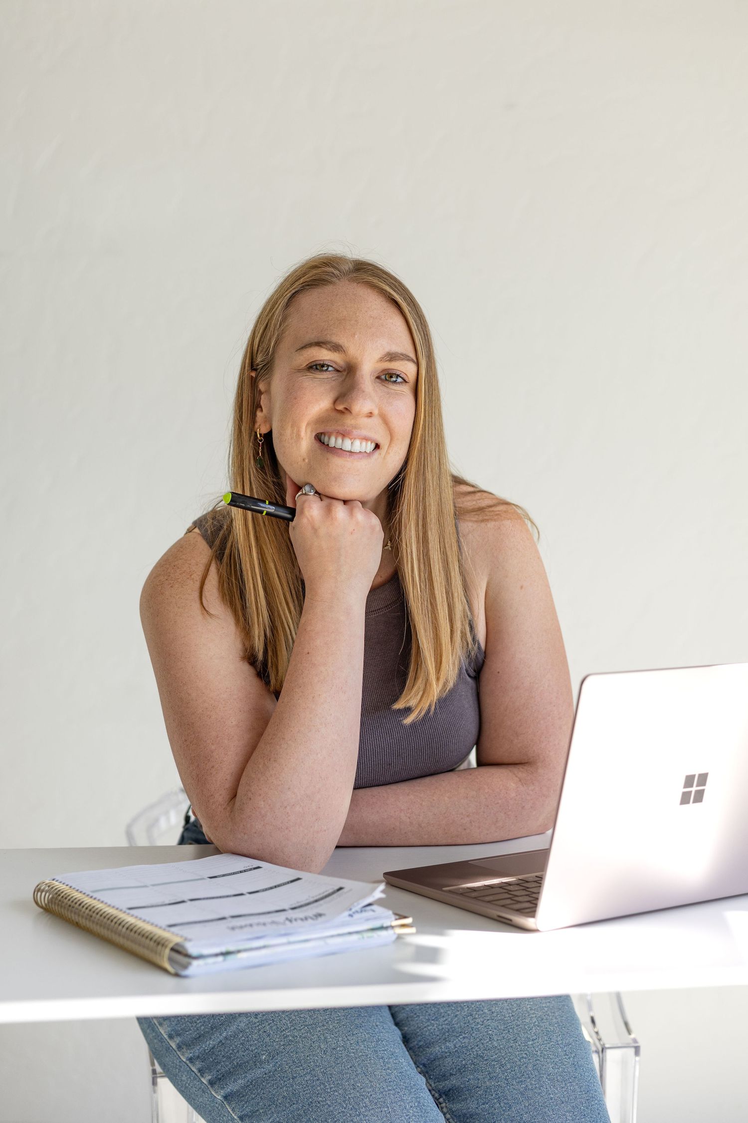 A professional setup with laptop and notebook on white desk in bright workspace.