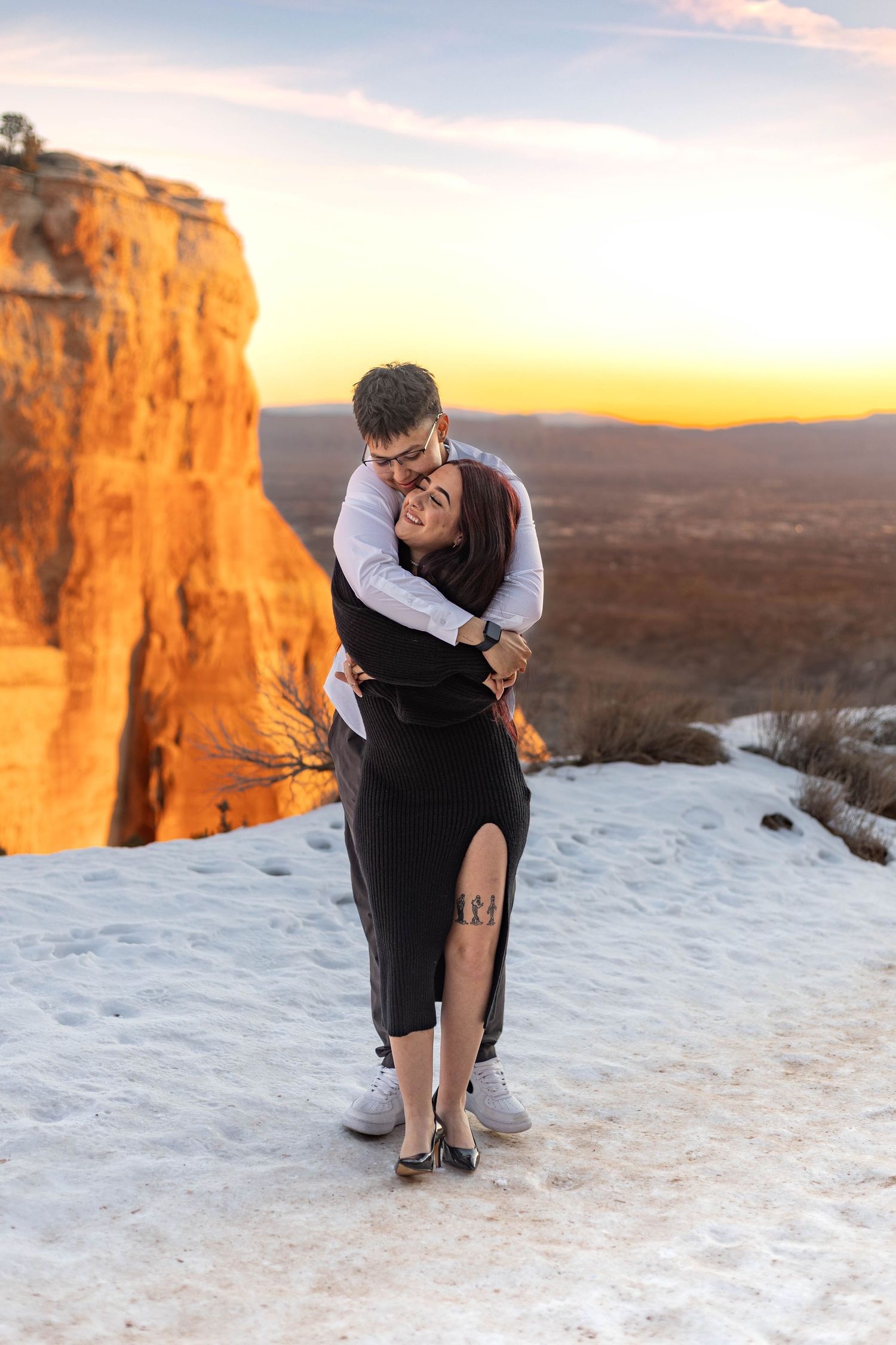 Romantic couple photo at sunset on snow-covered mountain overlook.
