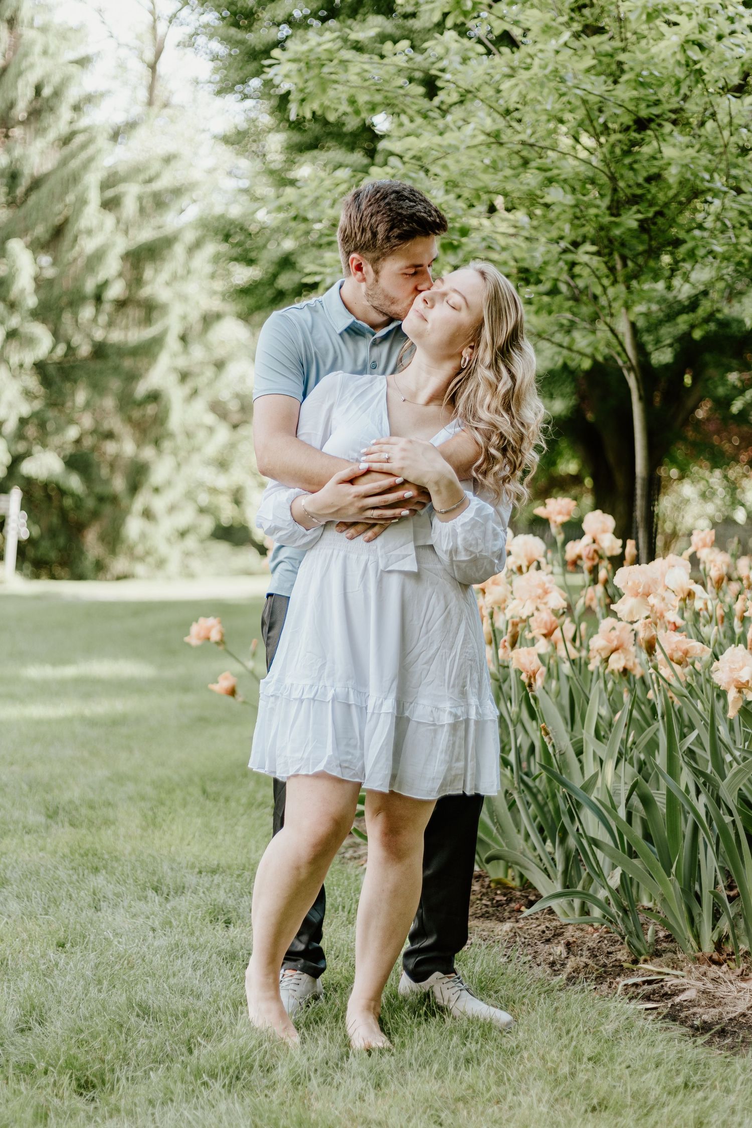 A couple shares an intimate moment in a garden with blooming peach irises.