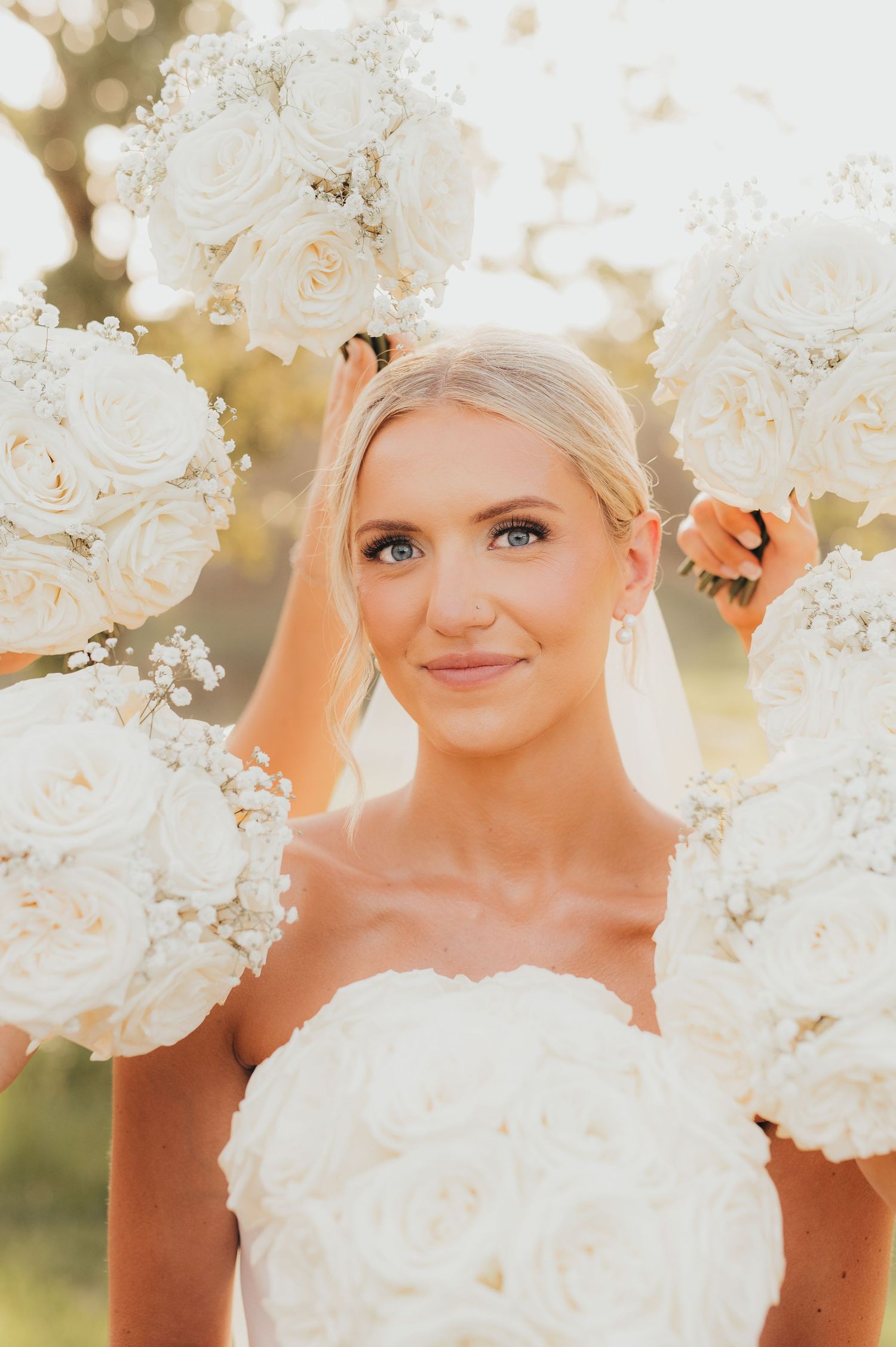 Bride smiling in her wedding dress surrounded by white flowers | East Texas wedding photographer