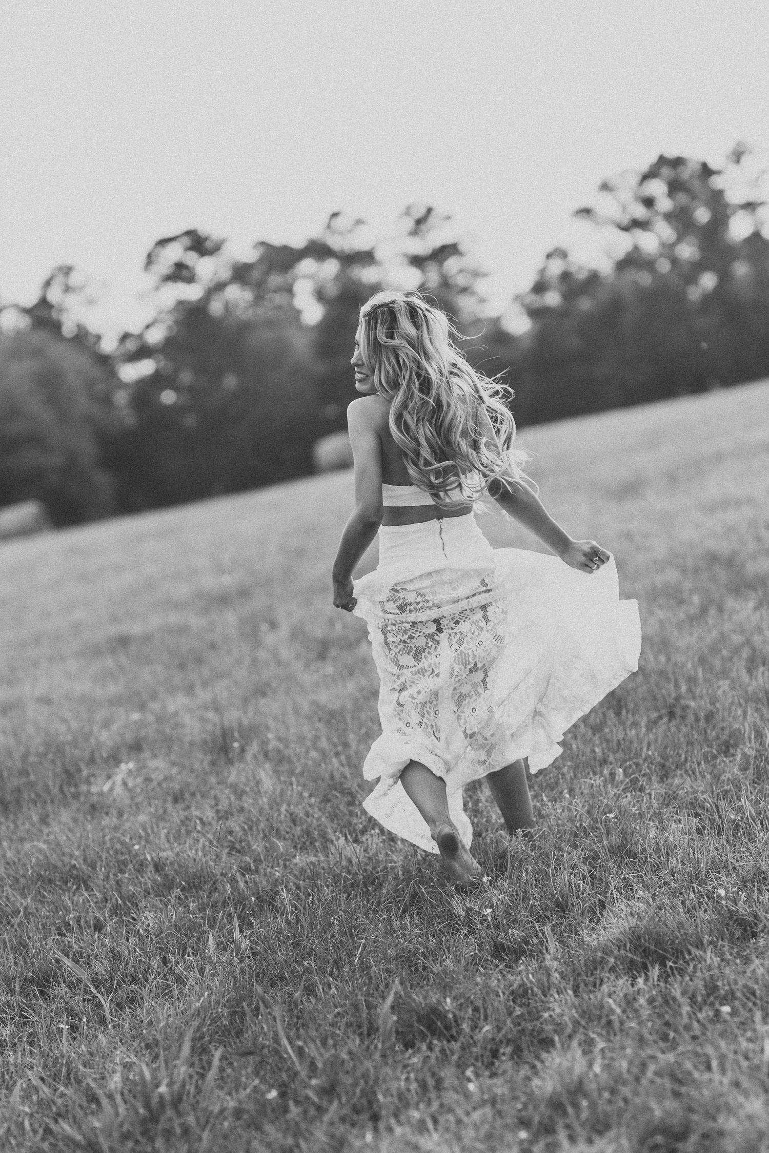 Black and white East Texas senior girl in a lace skirt running through a grassy field