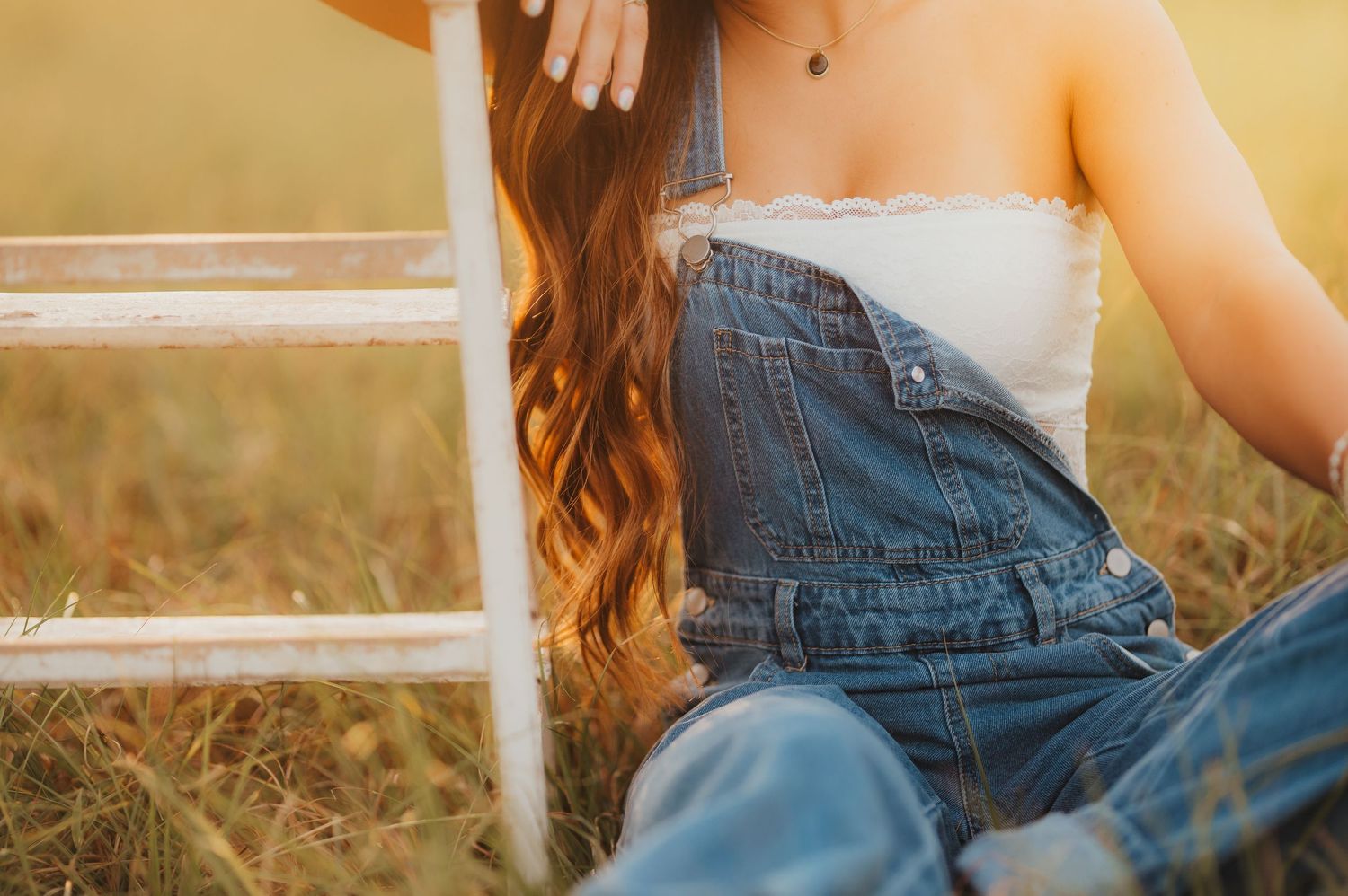 Senior girl in denim overalls sitting by a stool during her East Texas senior session