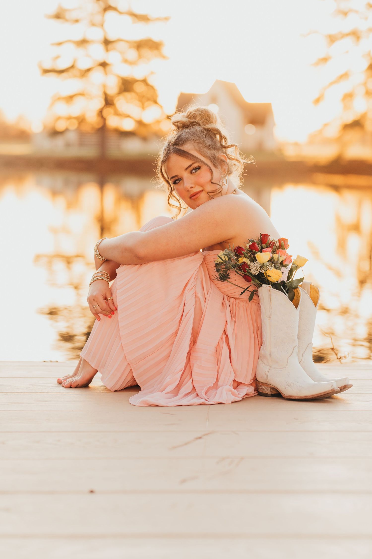 High school senior in a pink dress posing on dock during sunset at her senior session | East Texas senior photographer