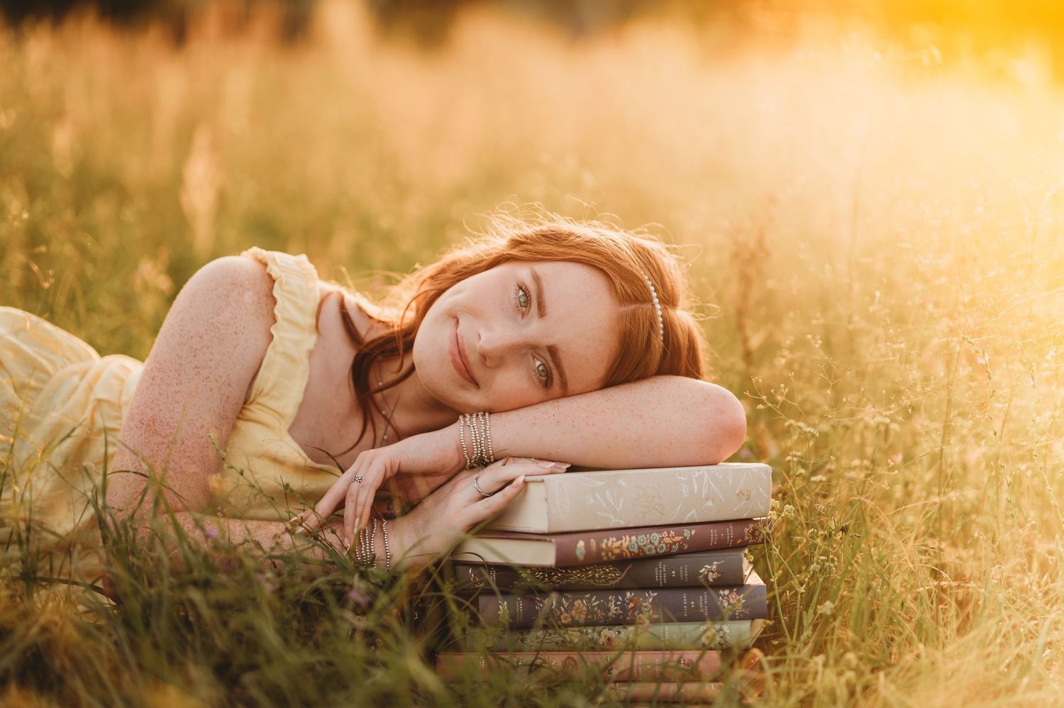 Senior girl lying in a field with book during a natural light senior photography session in East Texas