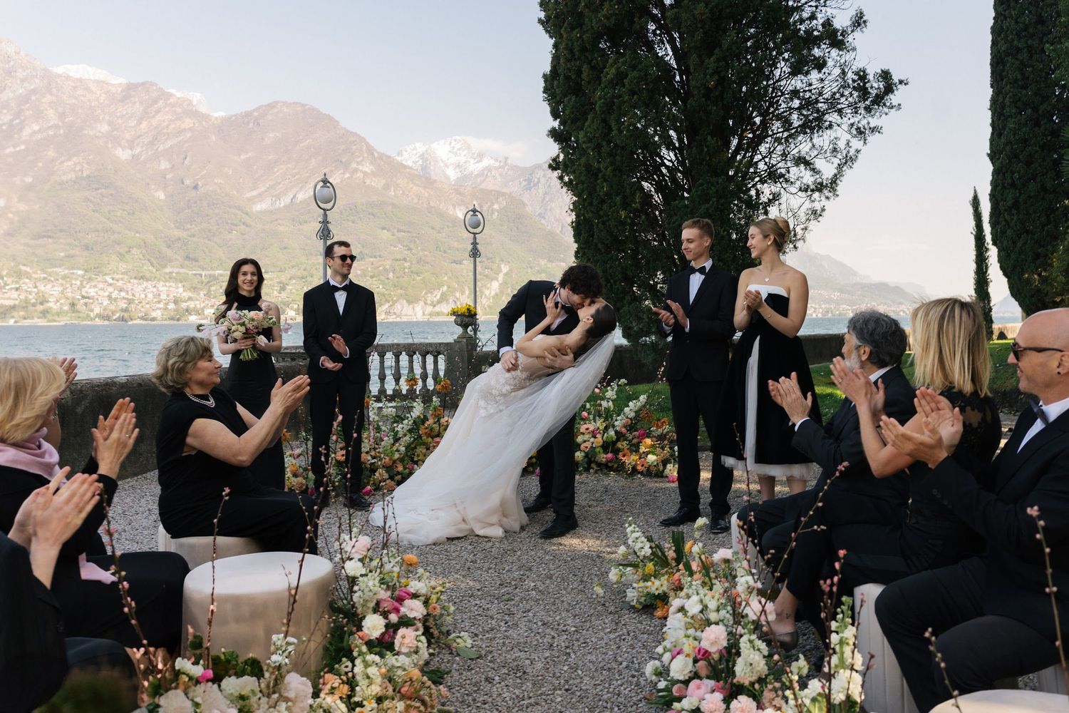Couple shares first kiss at Lake Como wedding ceremony with mountain backdrop.