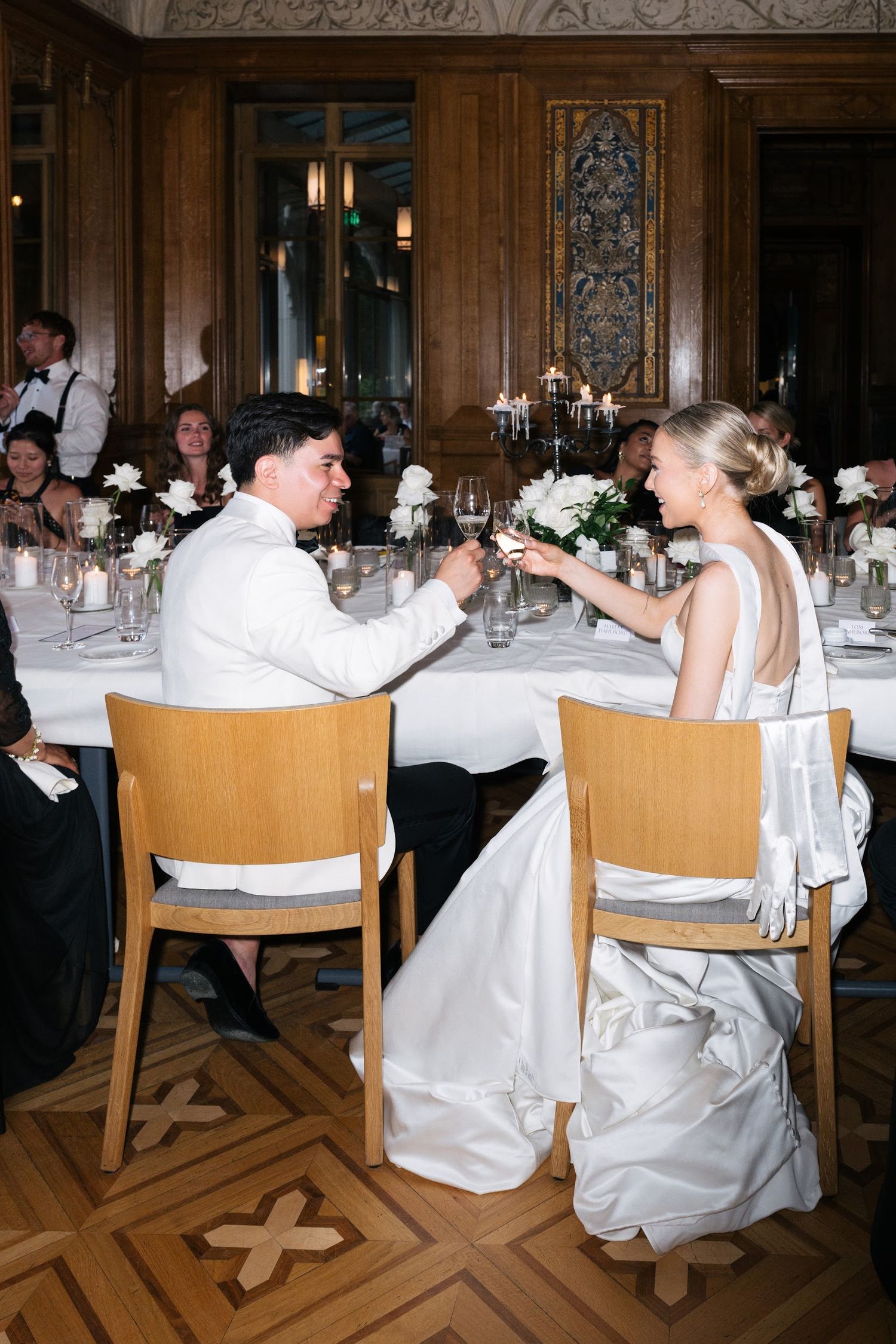 Bride and groom sharing a champagne toast at their elegant wedding reception dinner table.