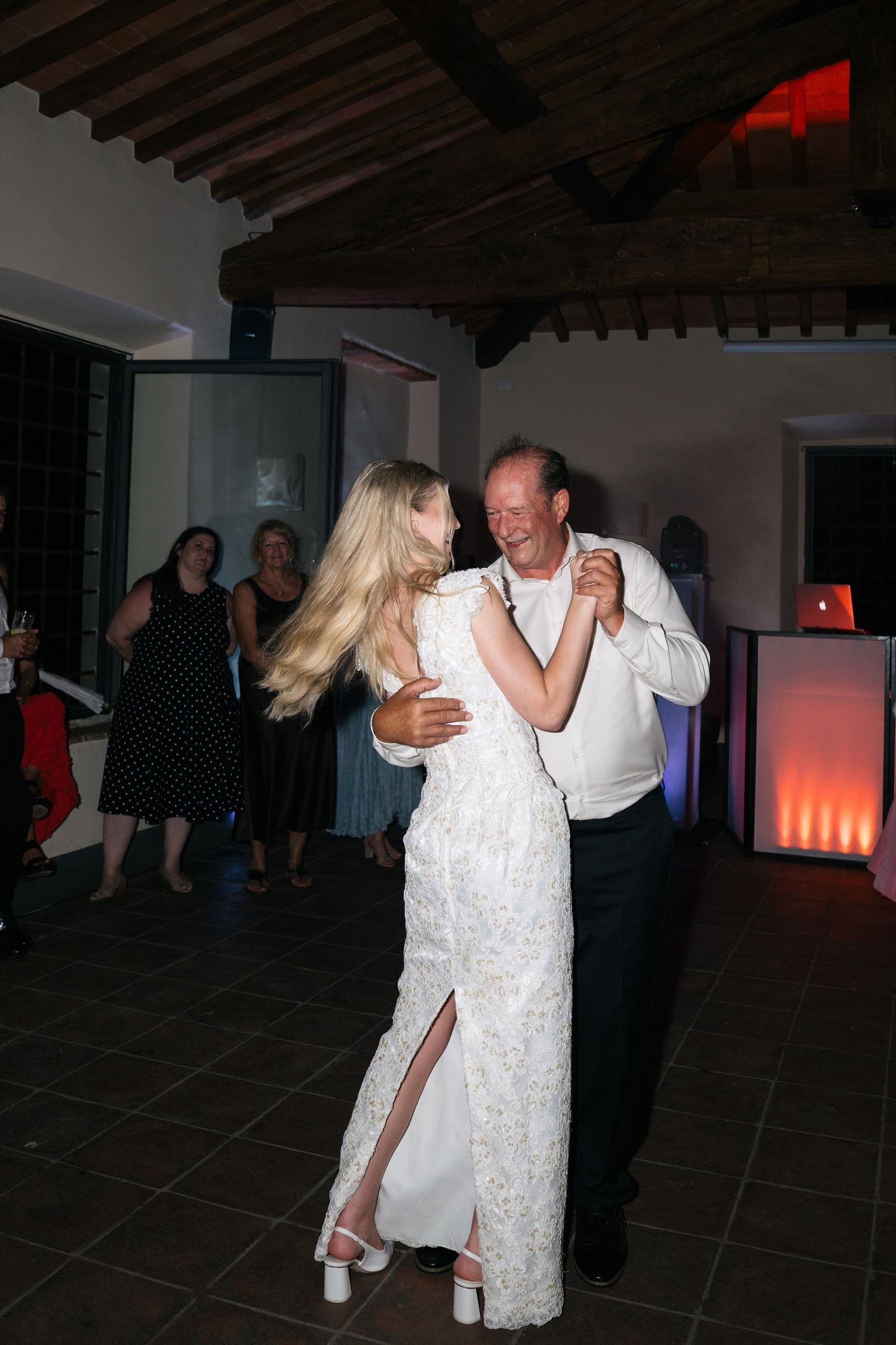 Bride in lace wedding gown sharing a tender father-daughter dance on the indoor reception dance floor.