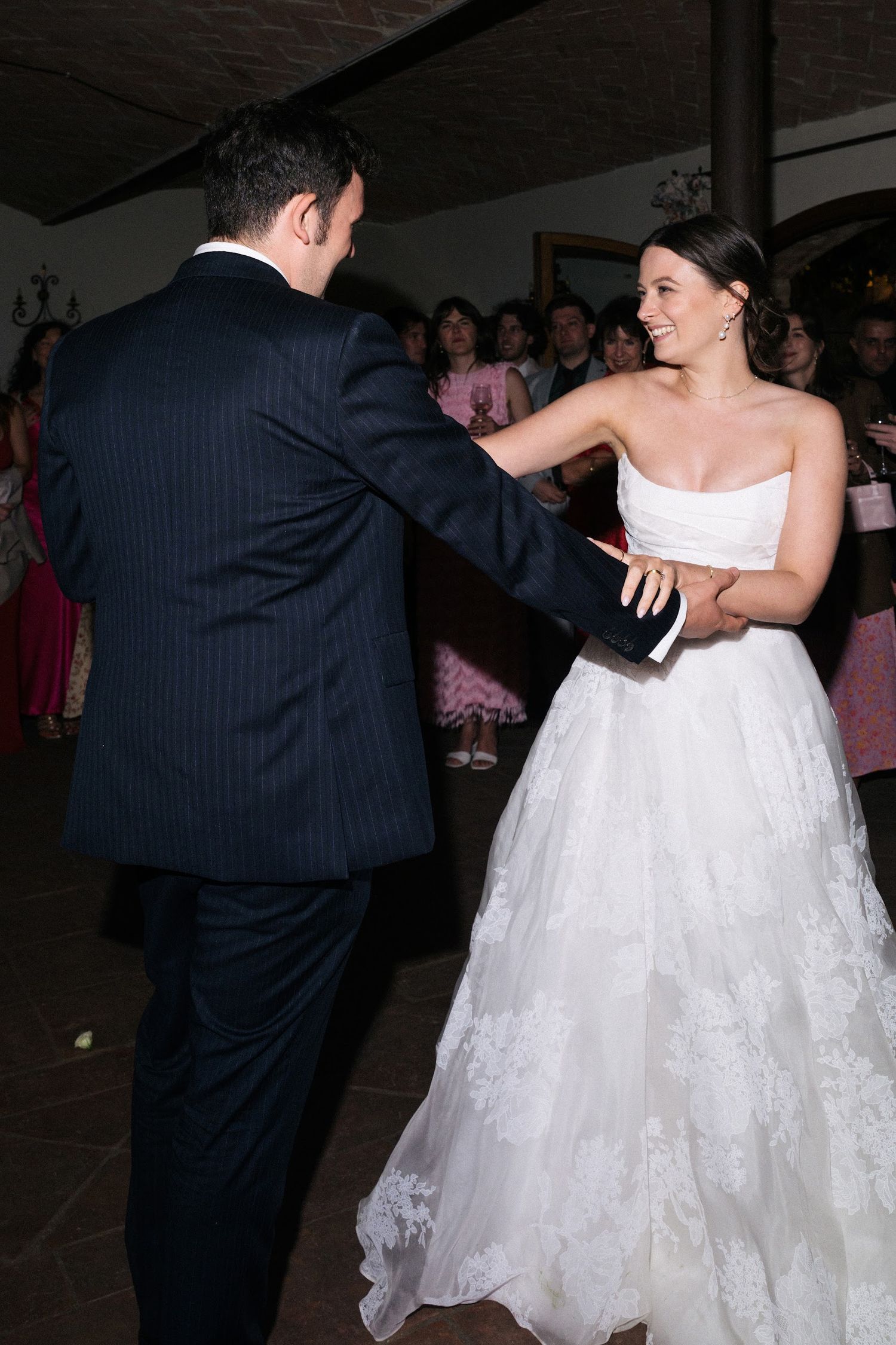 Bride smiles radiantly while sharing first dance with groom at wedding.