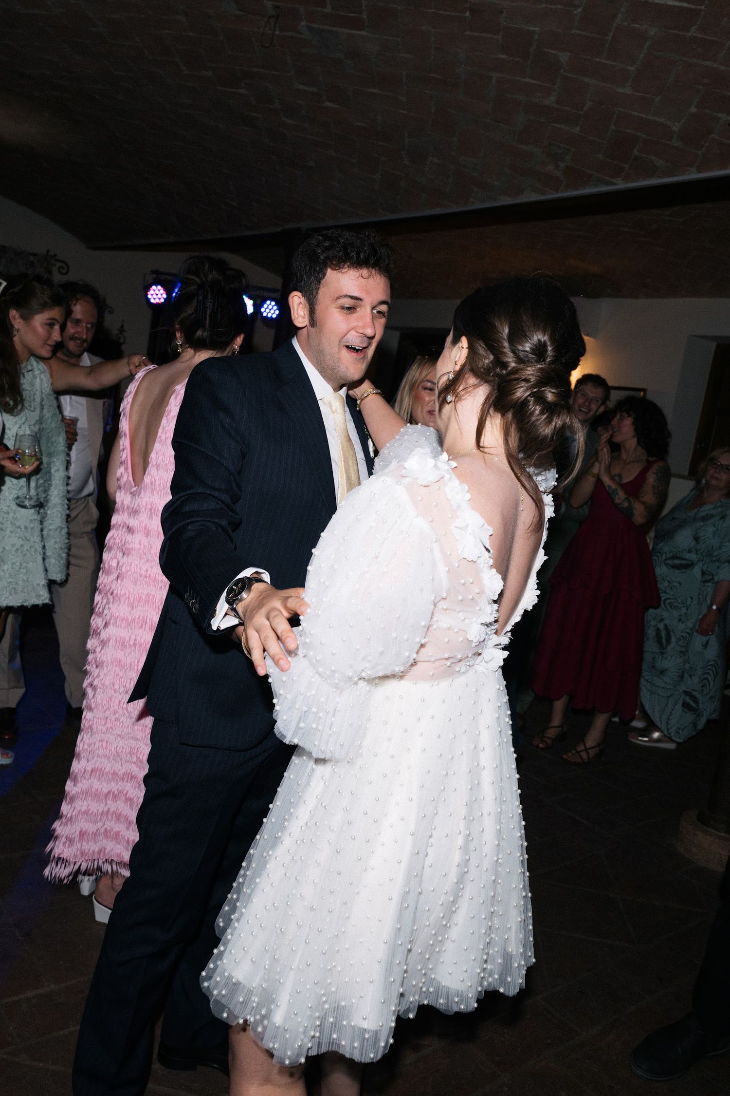 Bride in white pearl mini dress dancing with groom at wedding reception.