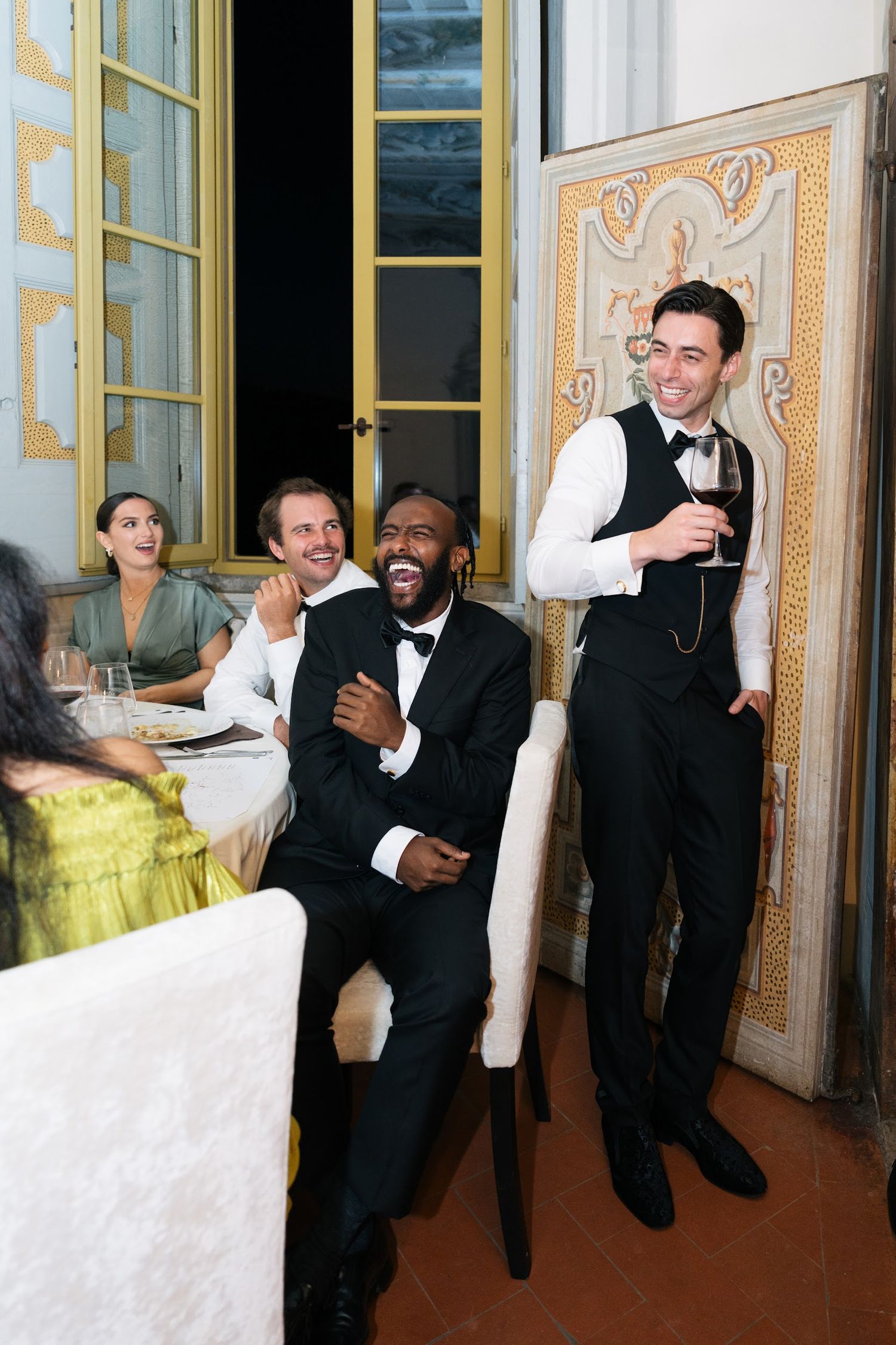 Groom sharing toast with friends at elegant Italian villa wedding reception dinner.