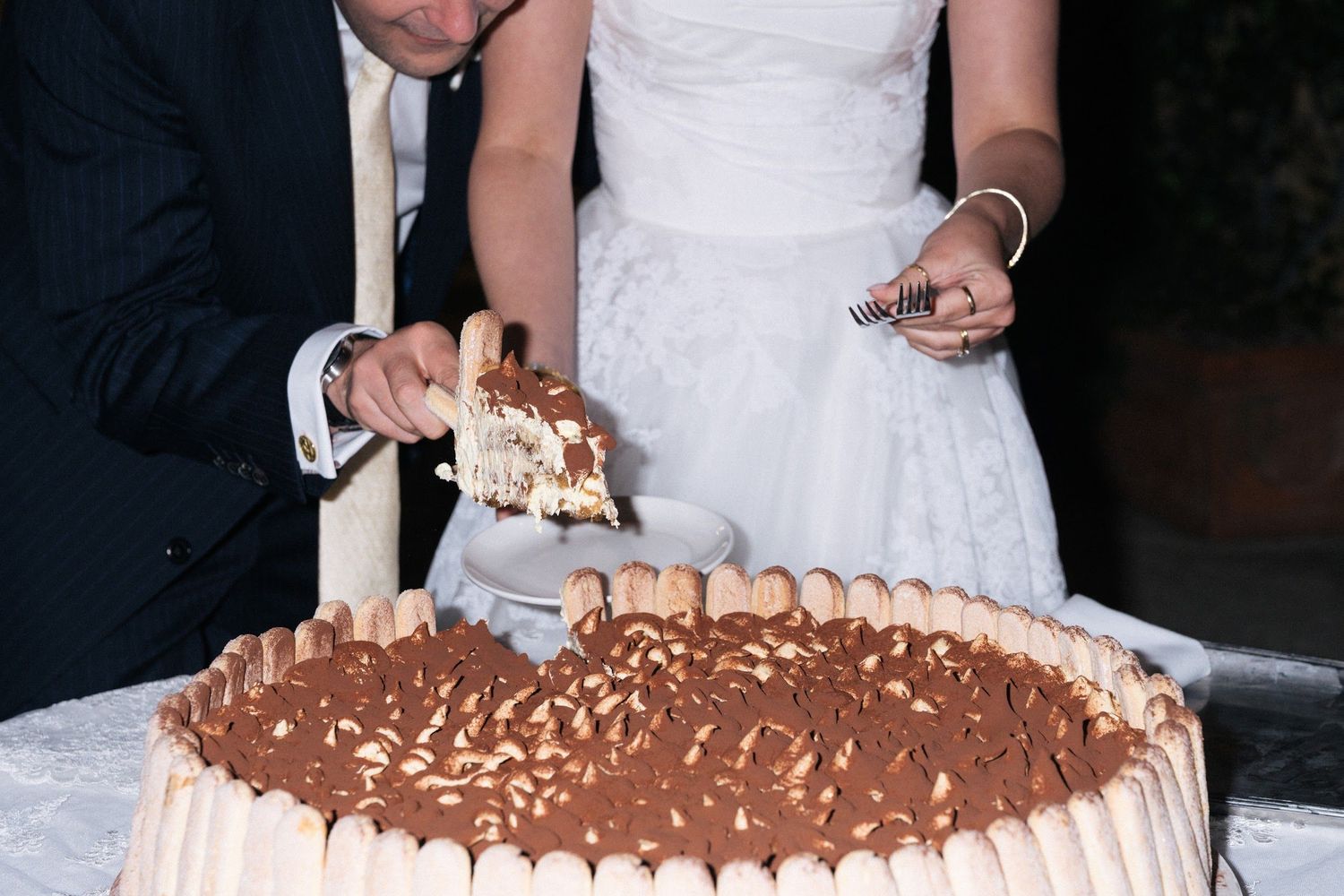 Bride and groom cut into a large tiramisu wedding cake together.