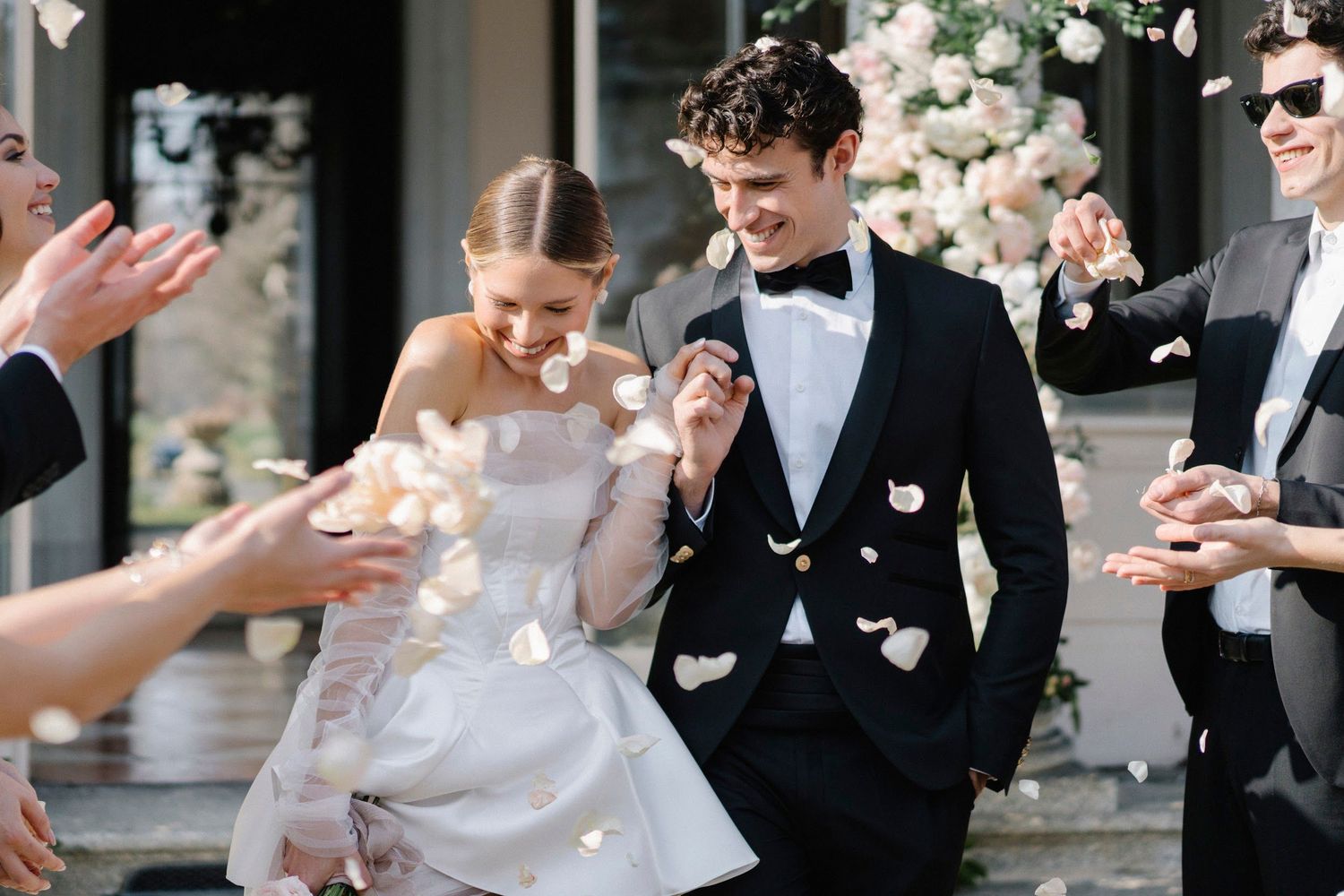 Bride and groom exit ceremony as guests toss white rose petals.