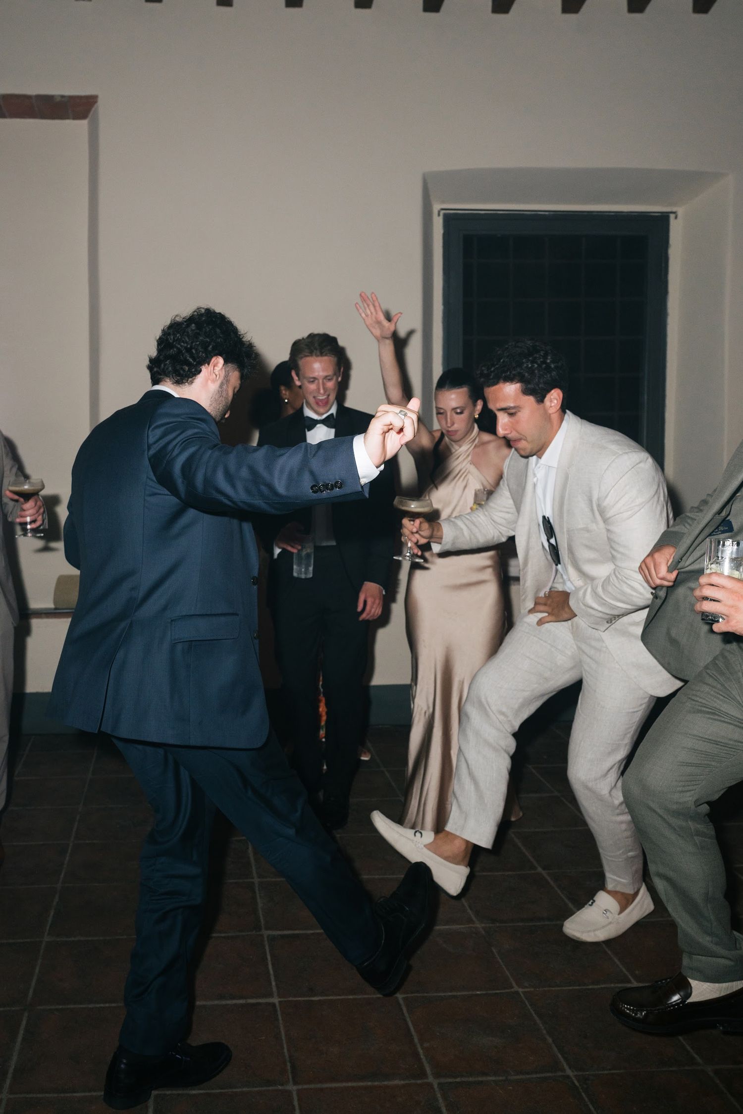 Wedding guests dancing energetically on the dance floor during a lively wedding reception celebration.