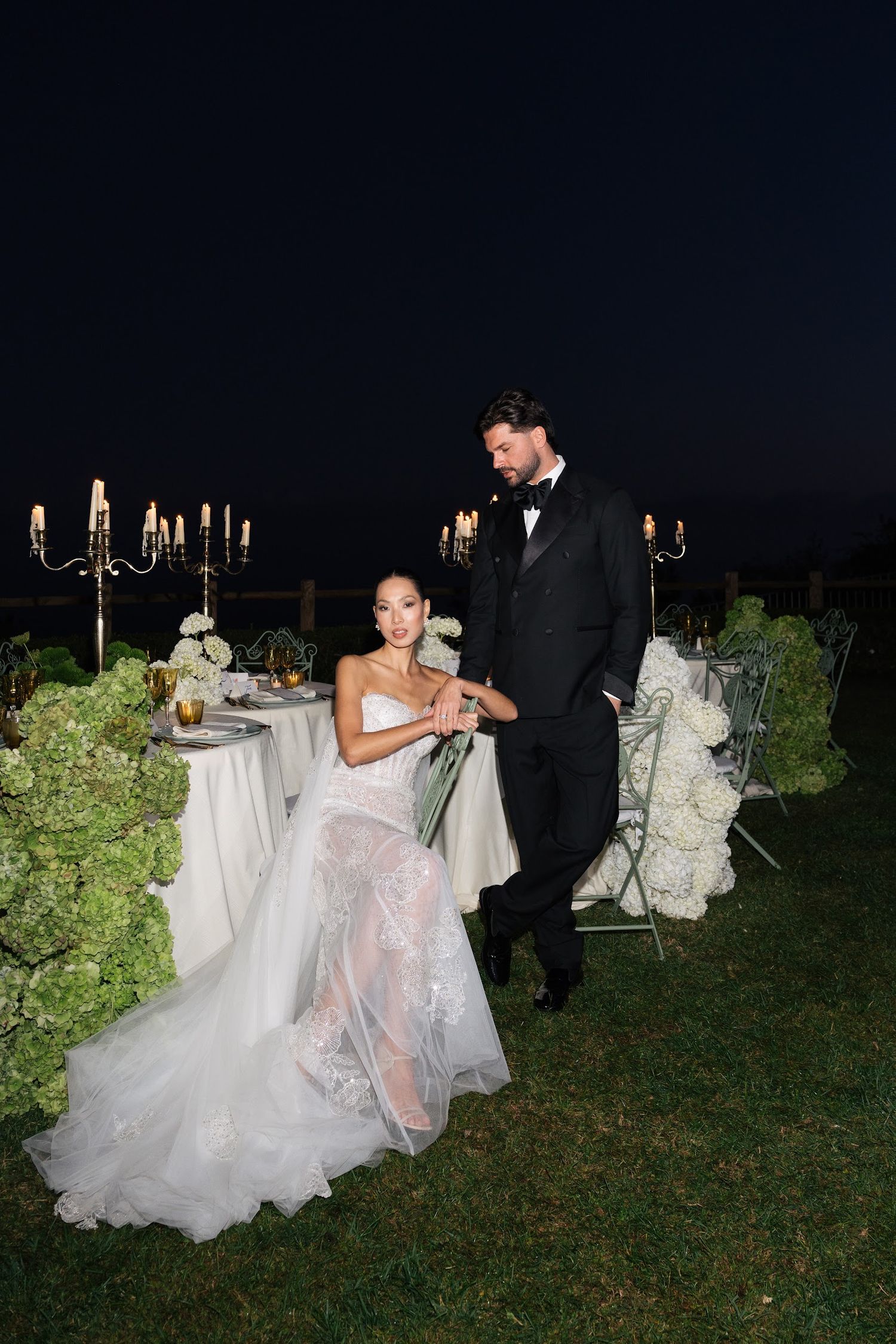Bride and groom share intimate moment at candlelit outdoor reception table at night in Ravello.