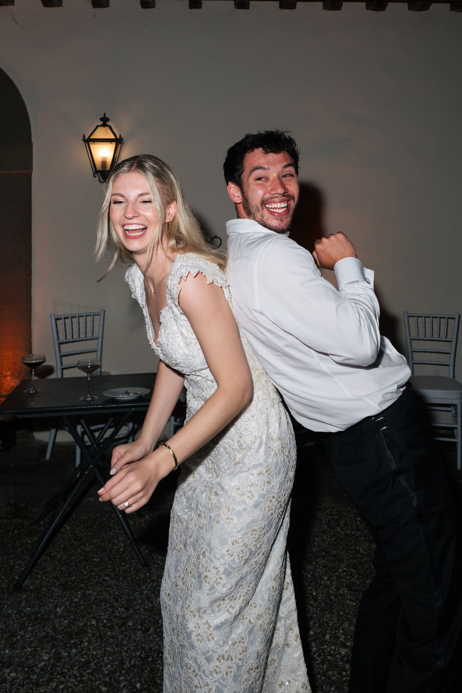 Bride and groom laughing and dancing back-to-back at their wedding reception party.