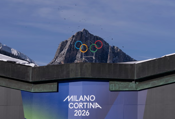 Milano Cortina 2026 Winter Olympics signage with Olympic rings on snowy mountain backdrop.