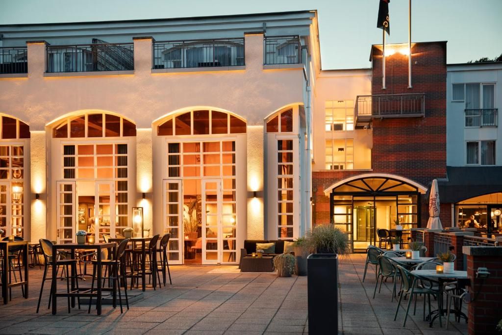 Elegant restaurant patio with arched windows glowing at dusk, outdoor seating and warm ambient lighting.