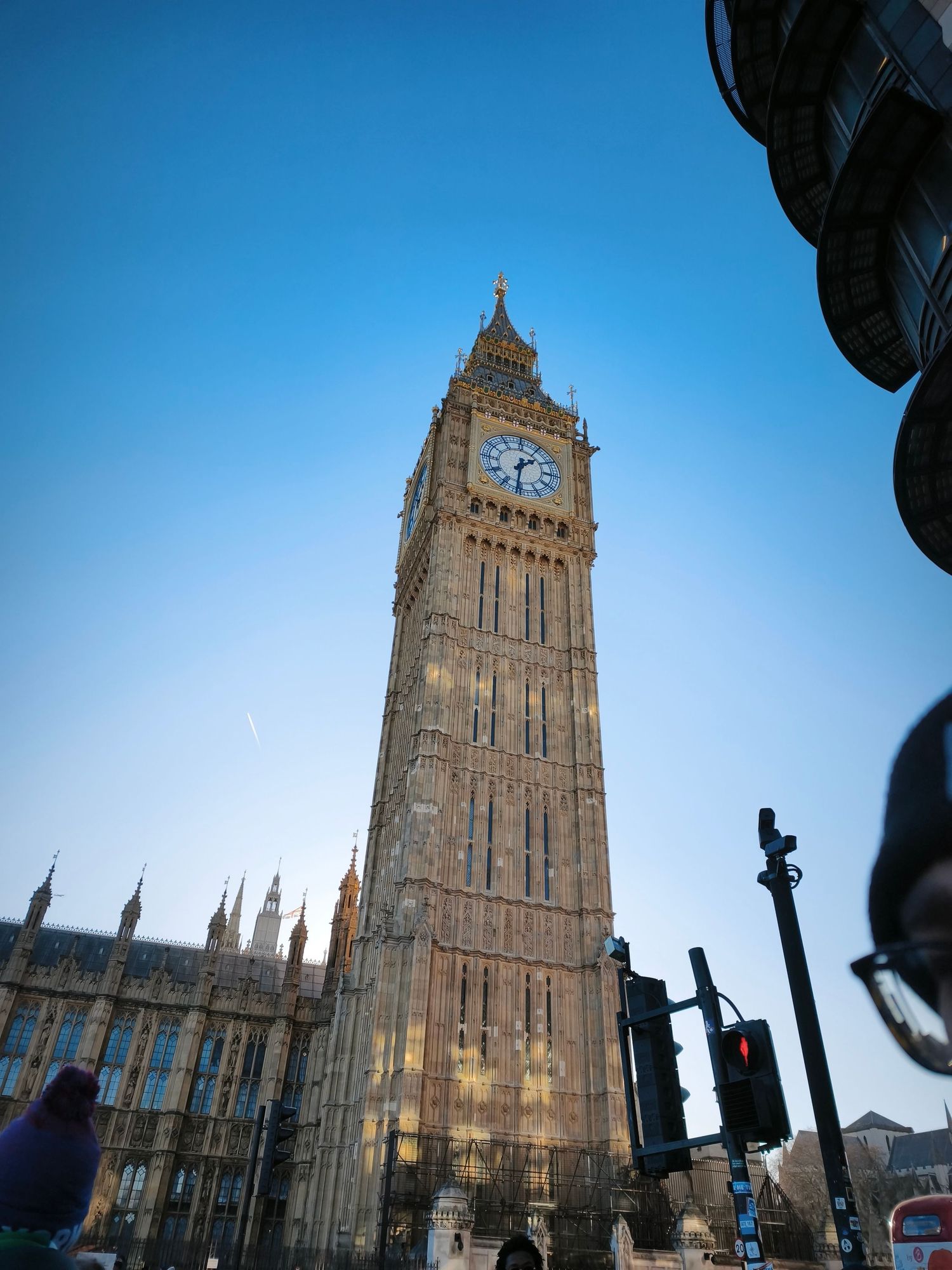 Big Ben clock tower in London against clear blue sky, low angle view with traffic lights visible.