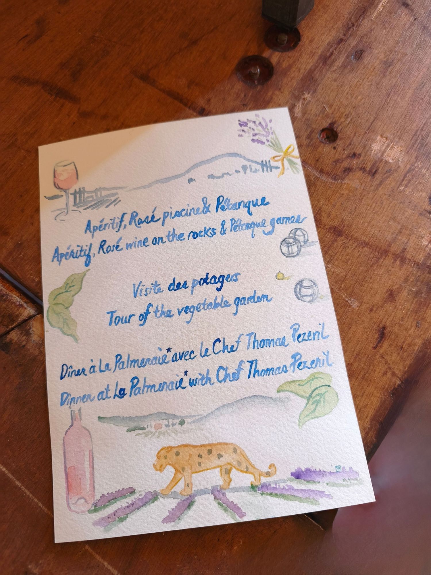 Illustrated watercolor event program card featuring Provencal garden dinner activities with lavender and leopard artwork.