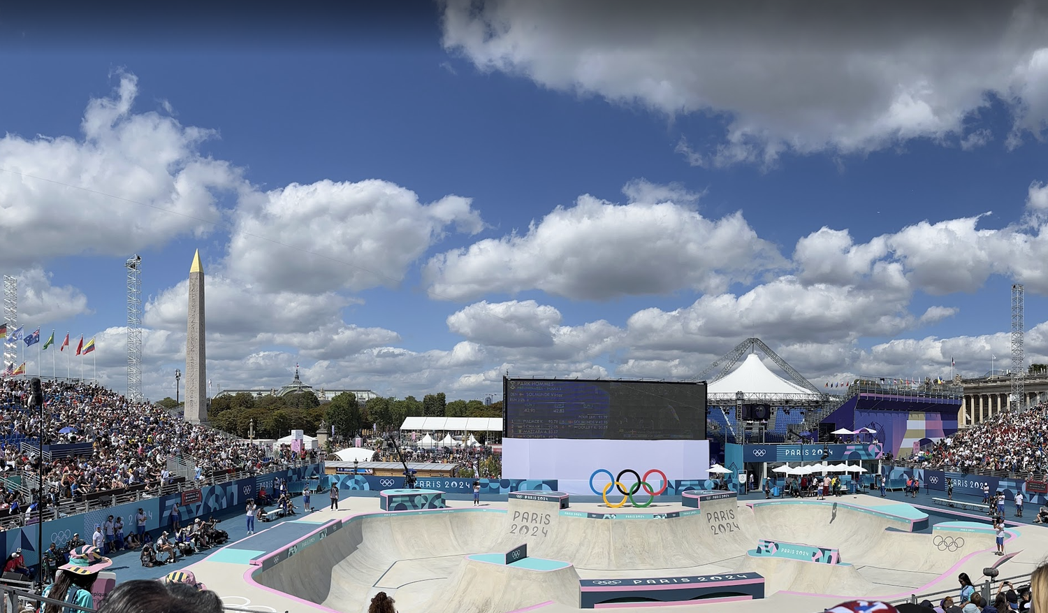 Aerial view of Olympic skateboarding venue in Paris with large crowd and iconic monument backdrop.