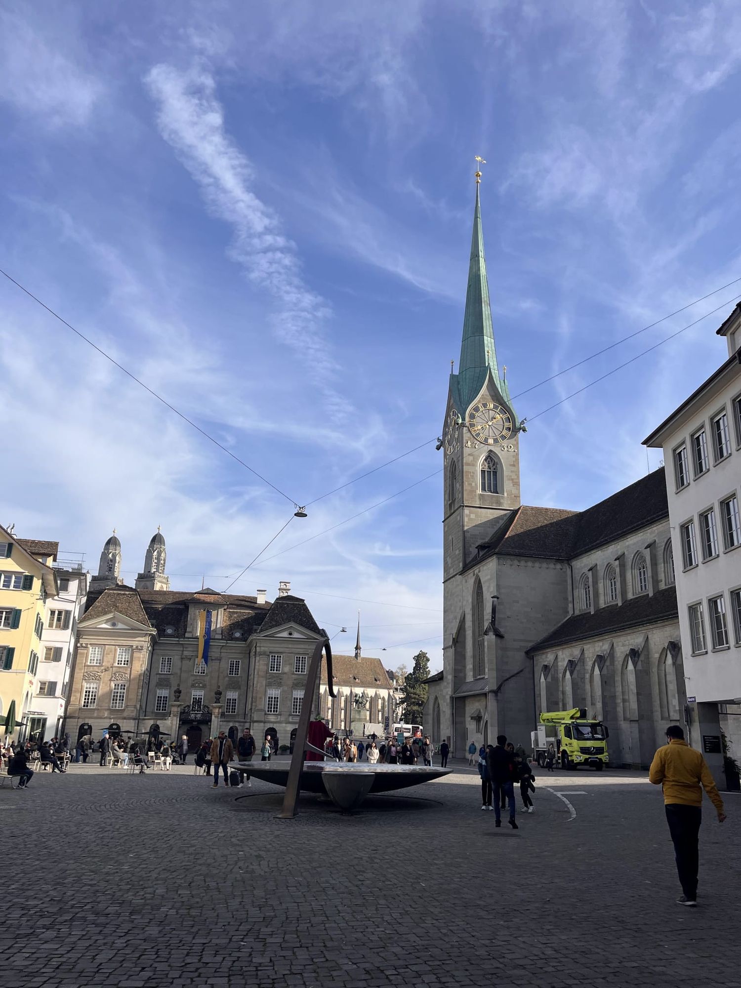 Fraumunster Church spire rising above Zurich old town square on sunny day.