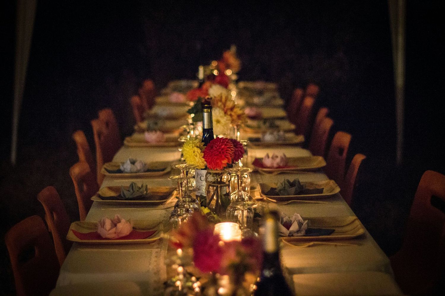 Long decorated dinner table with floral centerpieces and candles set for an intimate evening event.