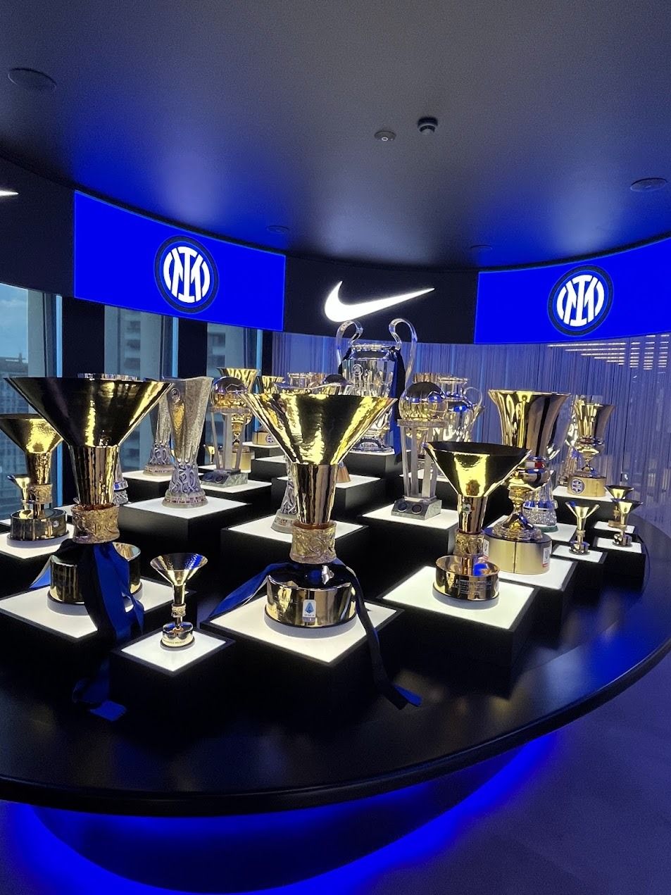 Inter Milan FC trophy cabinet displaying Champions League and Serie A trophies with Nike and club logos.