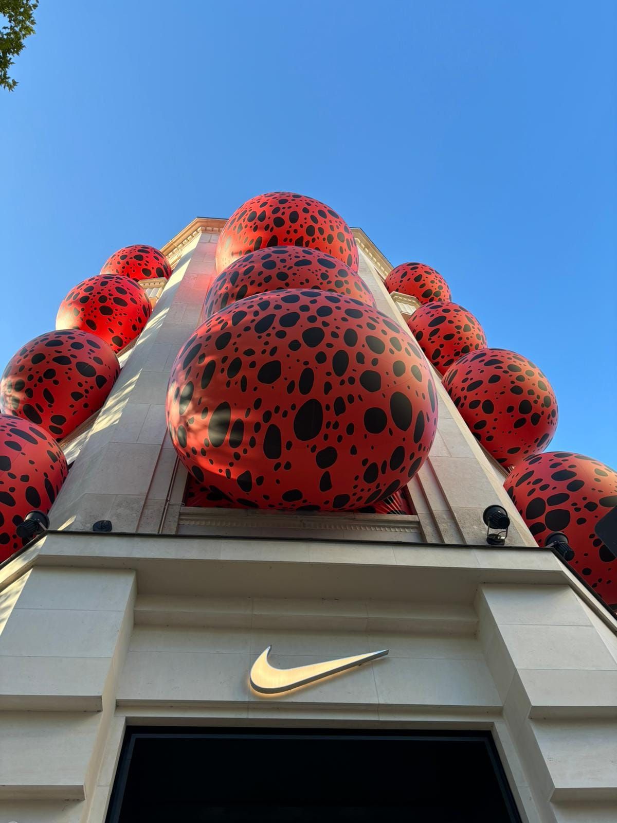 Nike store entrance covered in oversized red dotted balloons viewed from below.