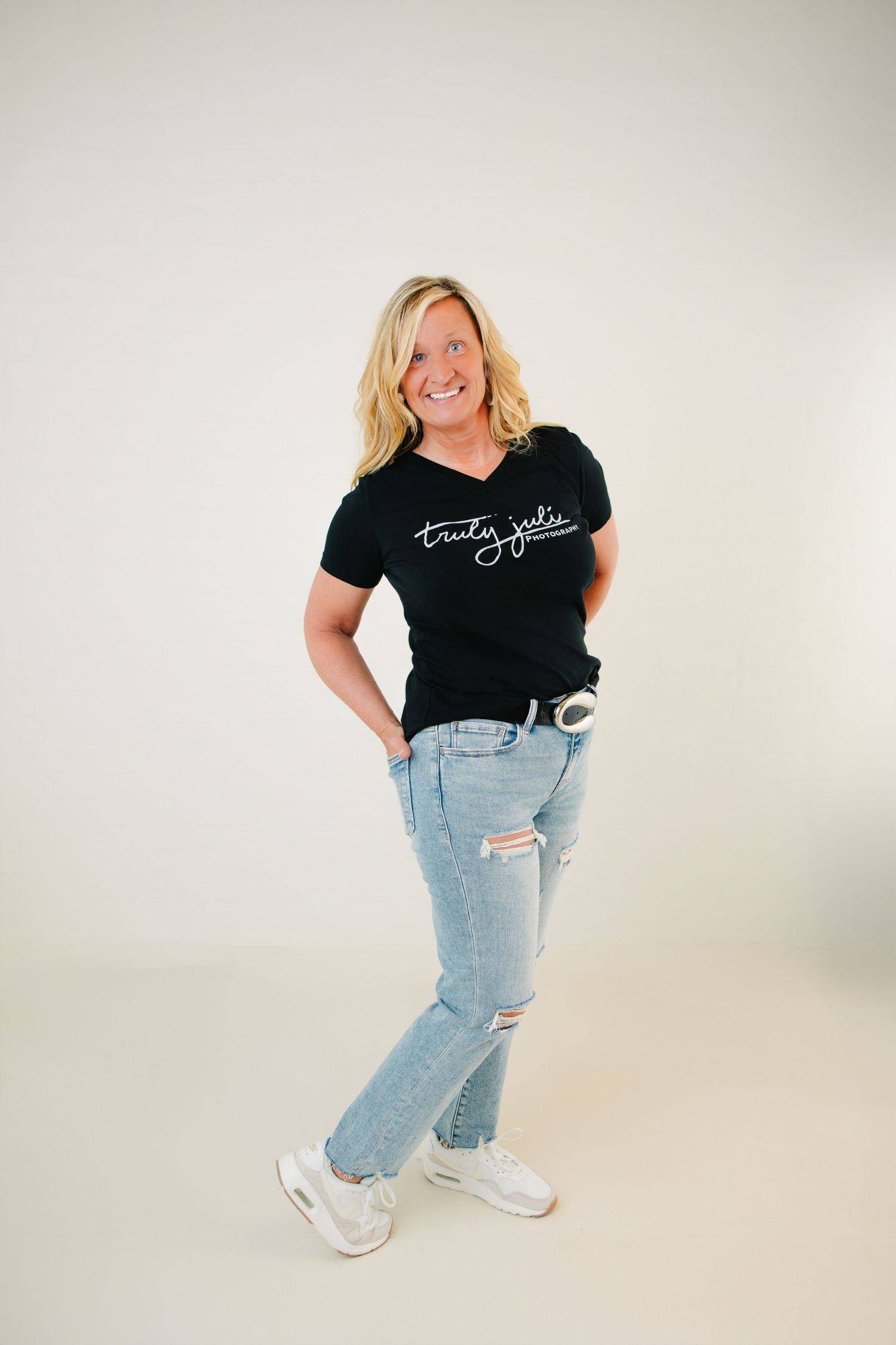 Photo of Senior and Family photographer with her hands in her back pockets wearing a black tee with her business logo on the front and jeans