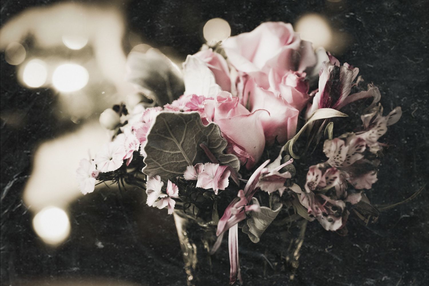 Vintage style pink roses and hydrangeas bouquet with soft bokeh lights in sepia tones.