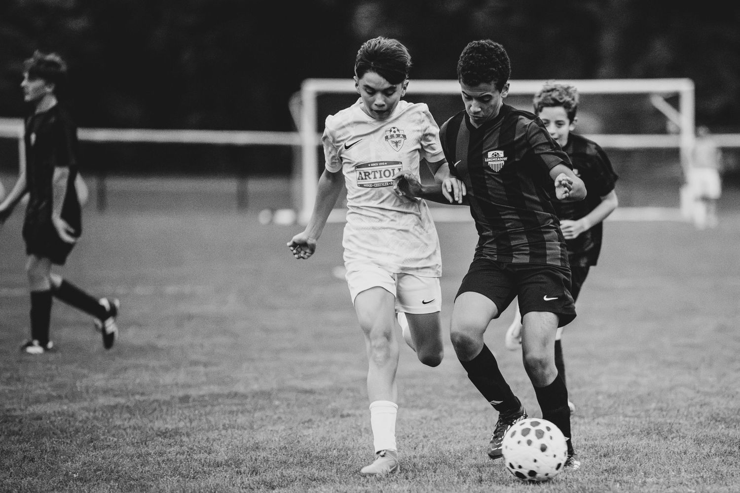 Two soccer players competing for the ball during a match in black and white photography.