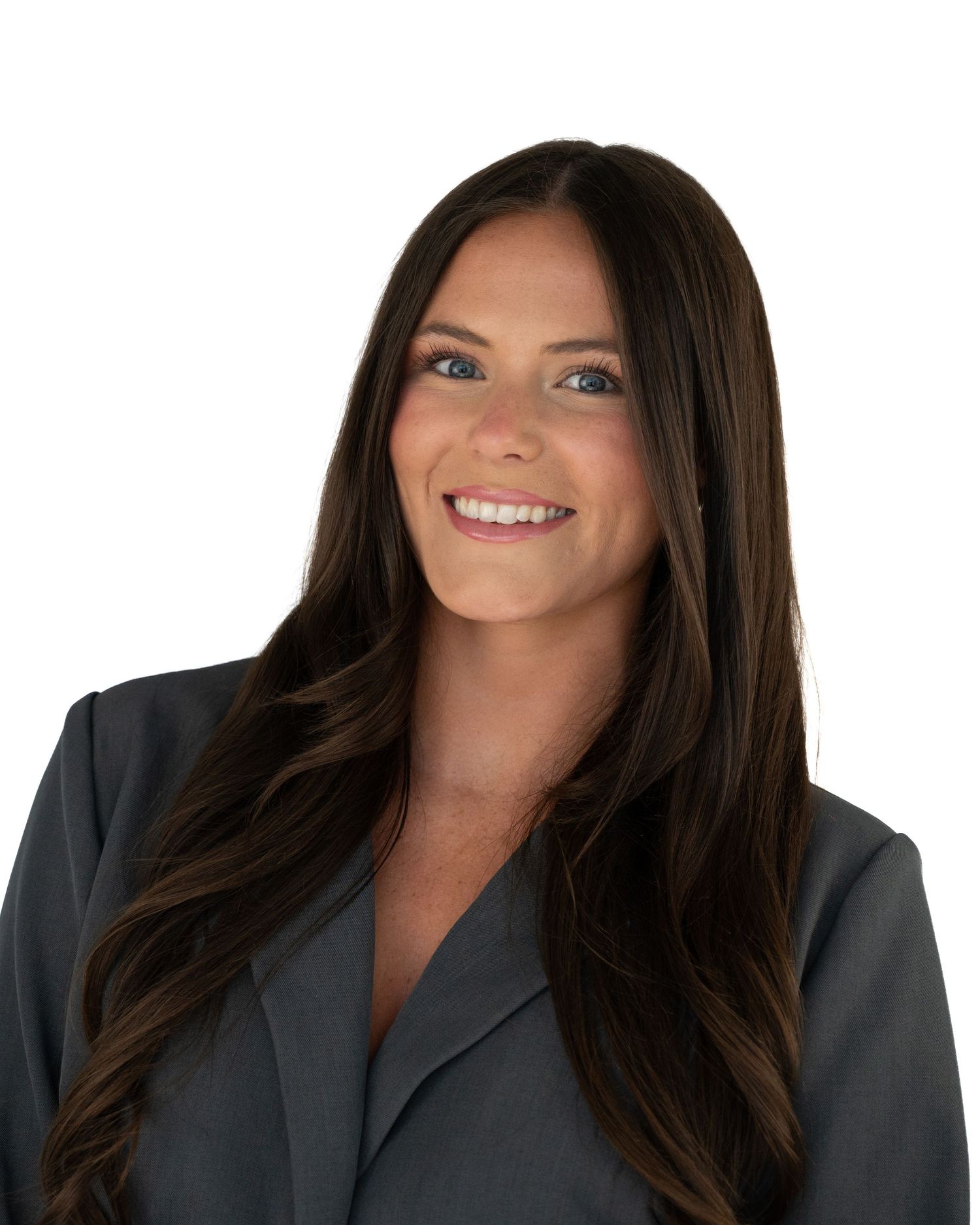 Professional headshot of a smiling woman with long dark hair wearing a gray blazer against a white background.